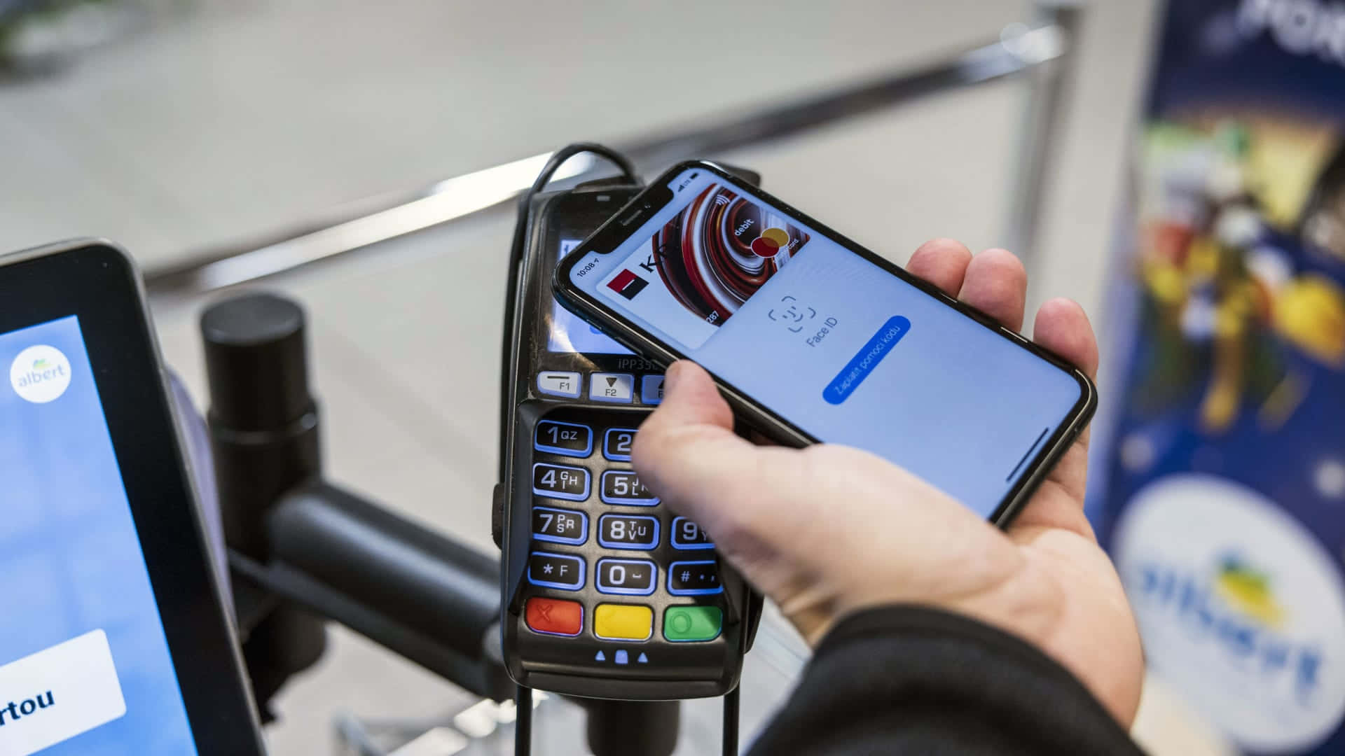 iPhone 桌布 壁紙 — 一隻手握住智慧型手機，在現代零售環境中輕觸非接觸式卡於支付終端上。