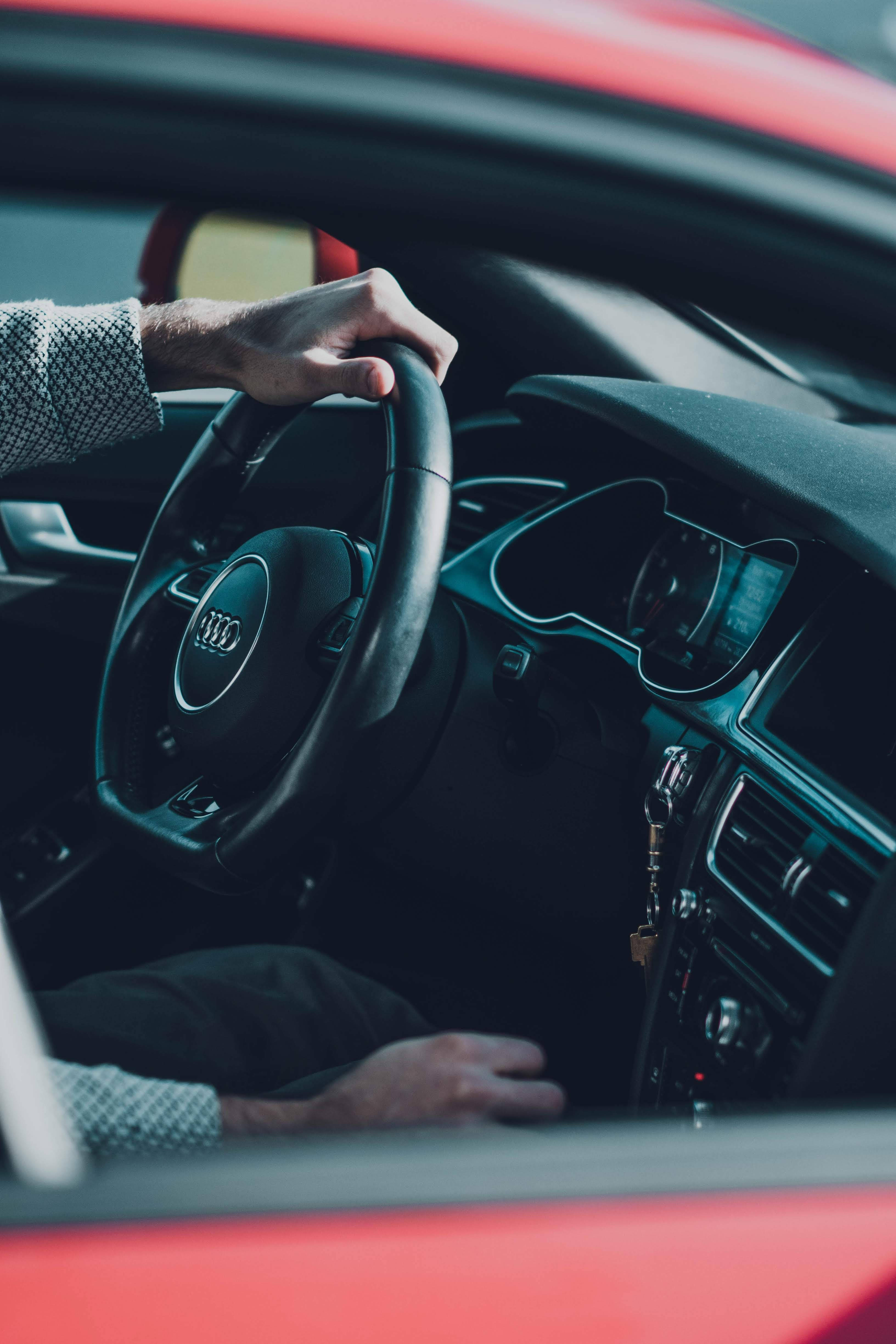 奧迪 桌布 壁紙 — 一隻手握住紅色 Audi 汽車的方向盤，鑰匙懸掛在點火開關上。