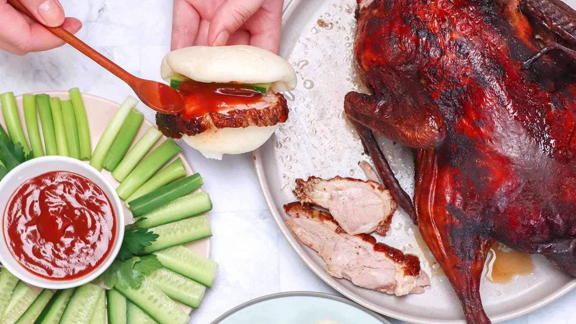 鴨子 桌布 壁紙 — 一隻手正在大理石桌上用小黃瓜條和甜醬組裝脆皮烤鴨三明治。