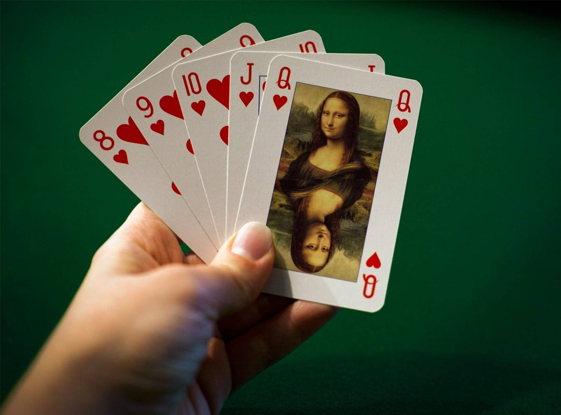 Poker 桌布 壁紙 — 一隻手正在搧動紅心撲克牌，包括一張帶有蒙娜麗莎臉部的皇后牌，背景為綠色絨氈。