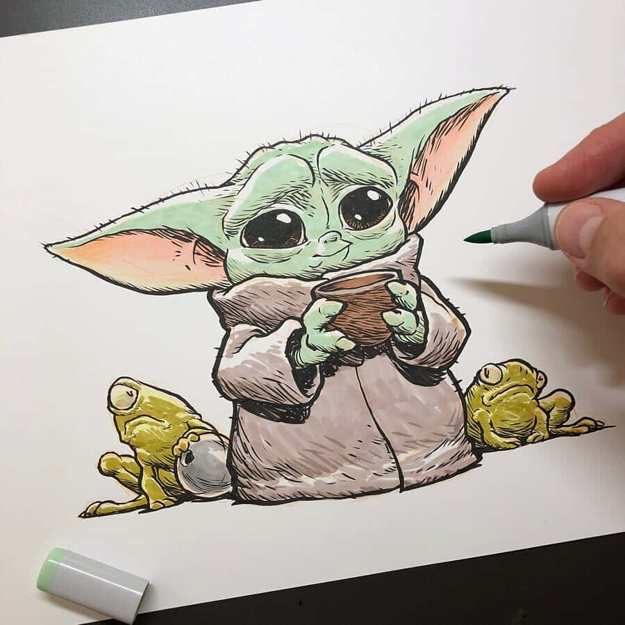 尤達寶寶 桌布 壁紙 — 一隻手正在為紙上可愛的插圖版 Baby Yoda 上色，它拿著一個杯子，旁邊有兩隻青蛙。