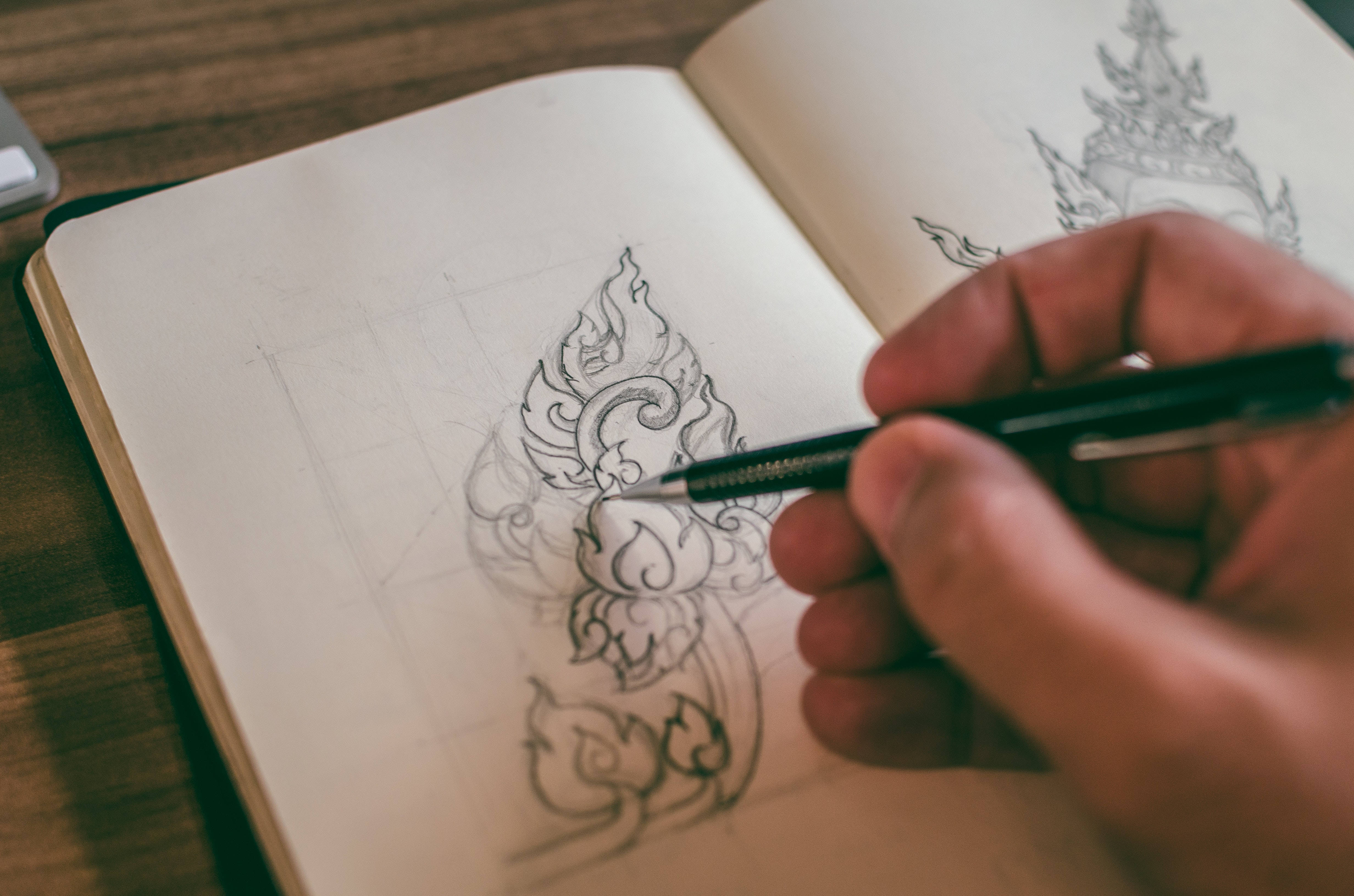 pencil 桌布 壁紙 — 一隻手用細筆在素描本上繪畫複雜的傳統泰式圖案。