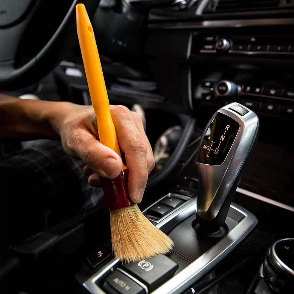 洗車 桌布 壁紙 — 一隻手用黃色刷子仔細清潔豪華車內裝的排檔桿和中控台。