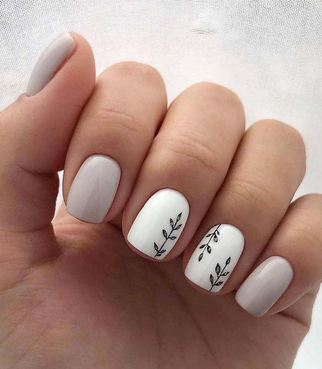 Spring Nails 桌布 壁紙 — 一隻手的特寫，指甲為簡約白色和淺灰色，兩根手指上有精緻的黑色樹枝葉設計。