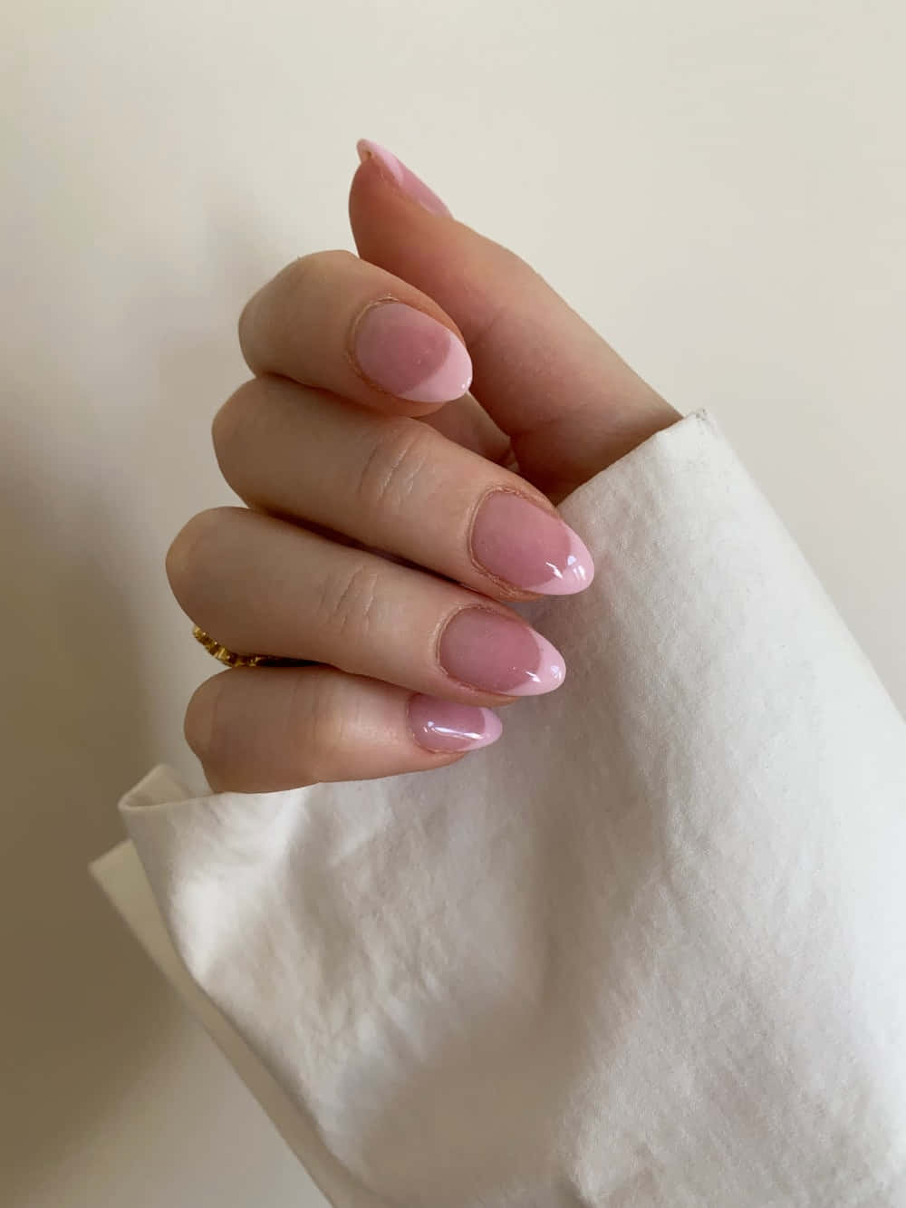 Nail 桌布 壁紙 — 一隻手的特寫，有柔和粉紅色光澤的指甲和金戒指，放在白色布料袖子上。