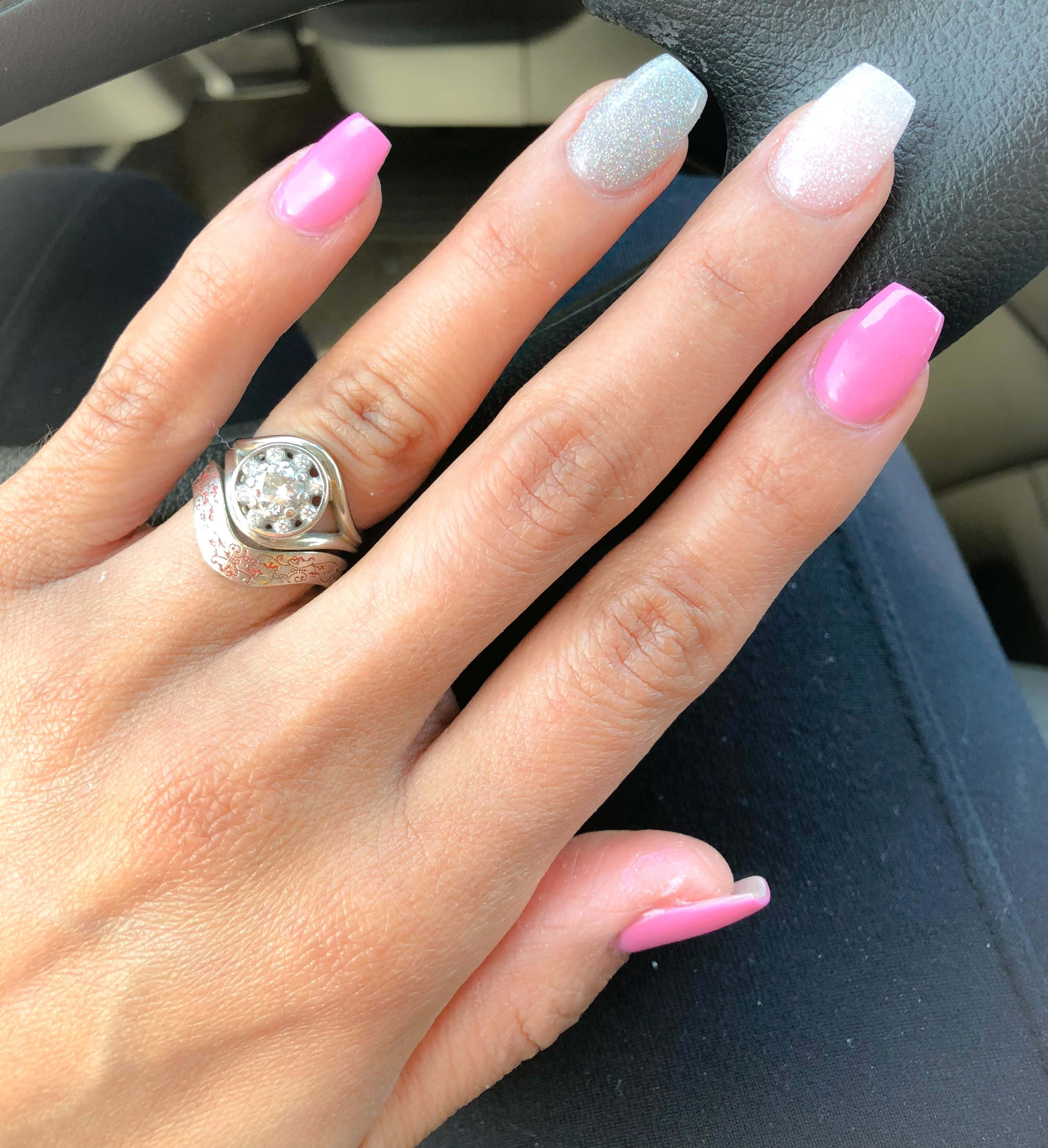 Spring Nails 桌布 壁紙 — 一隻手的特寫，有粉紅色和閃銀色指甲和鑽石戒指，放在汽車方向盤上。