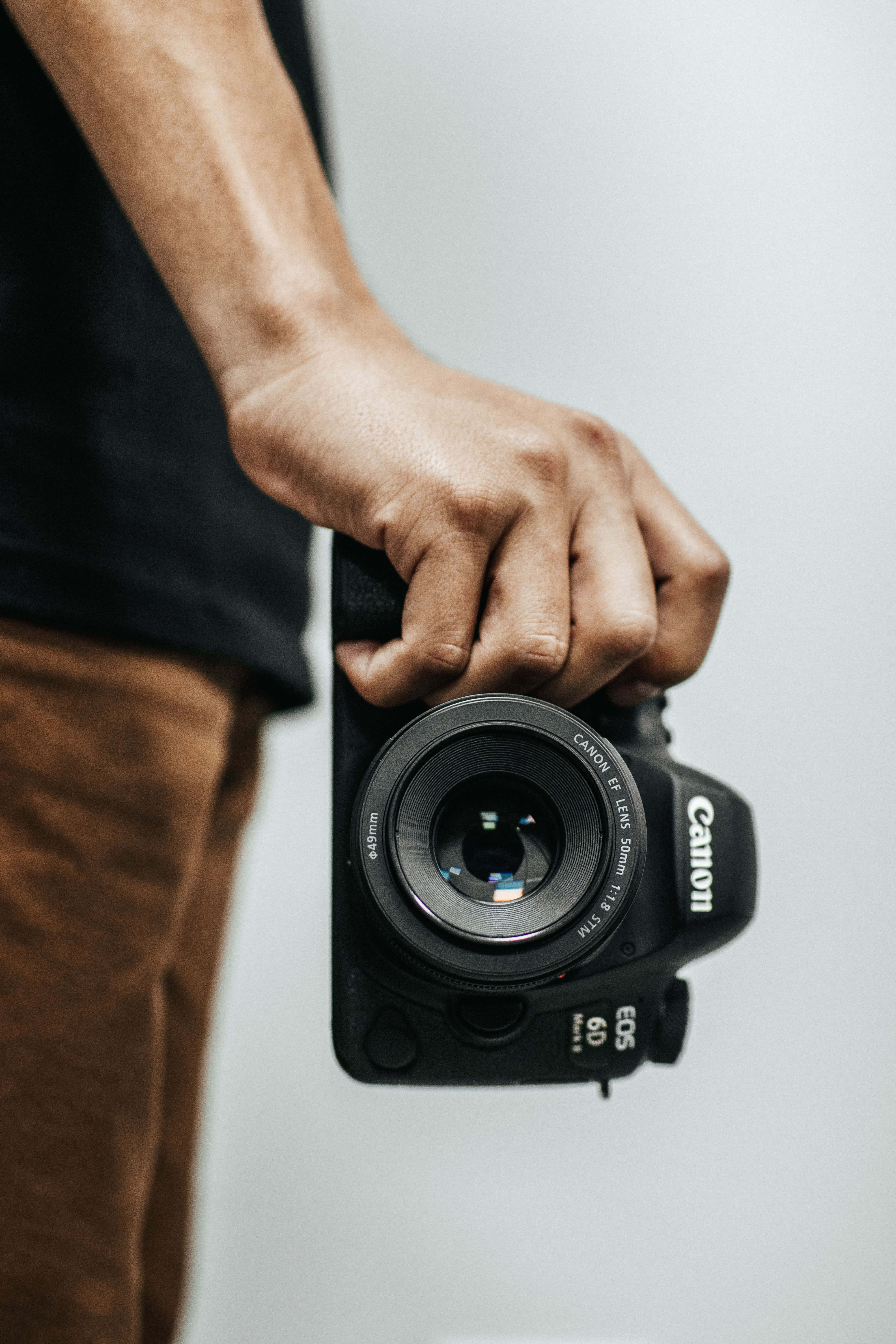 Dslr 桌布 壁紙 — 一隻手緊握黑色Canon EOS 6D DSLR相機的特寫，背景為純白色。