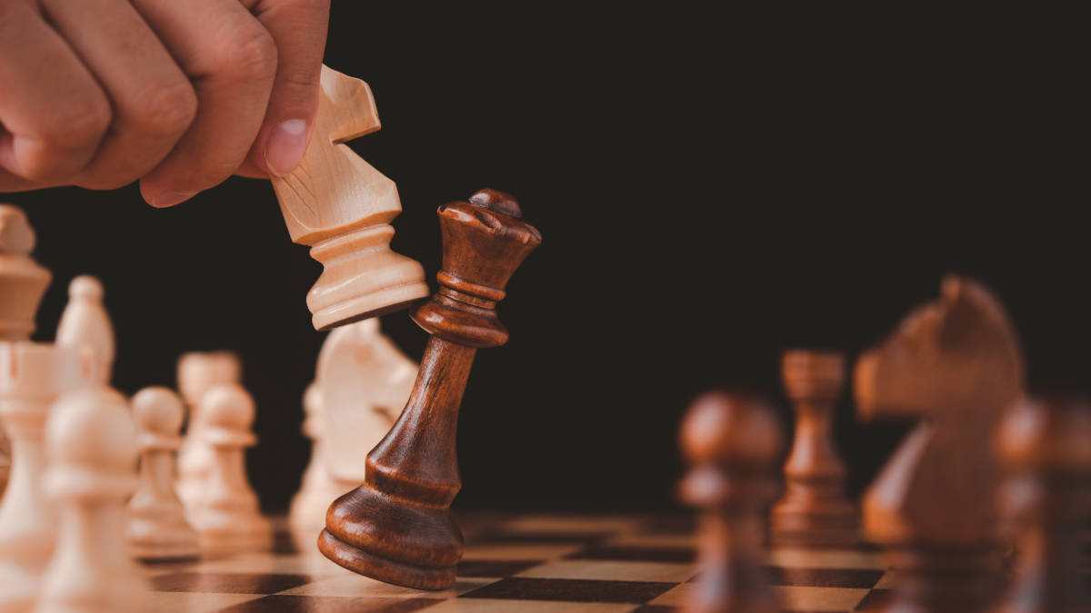 Chess 桌布 壁紙 — 一隻手舉起白色兵棋，在黑色背景的棋盤上吃掉黑色王棋。