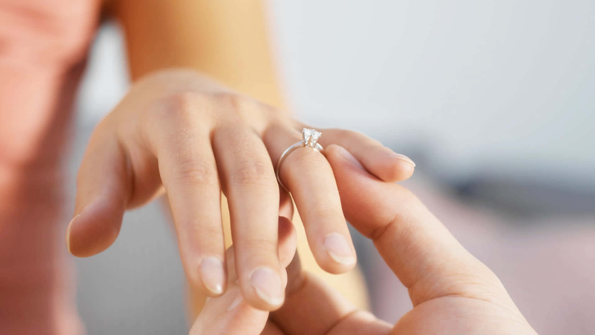 Marriage 桌布 壁紙 — 一隻手輕輕地將閃閃發光的鑽石訂婚戒指戴在另一個人手指上的特寫。