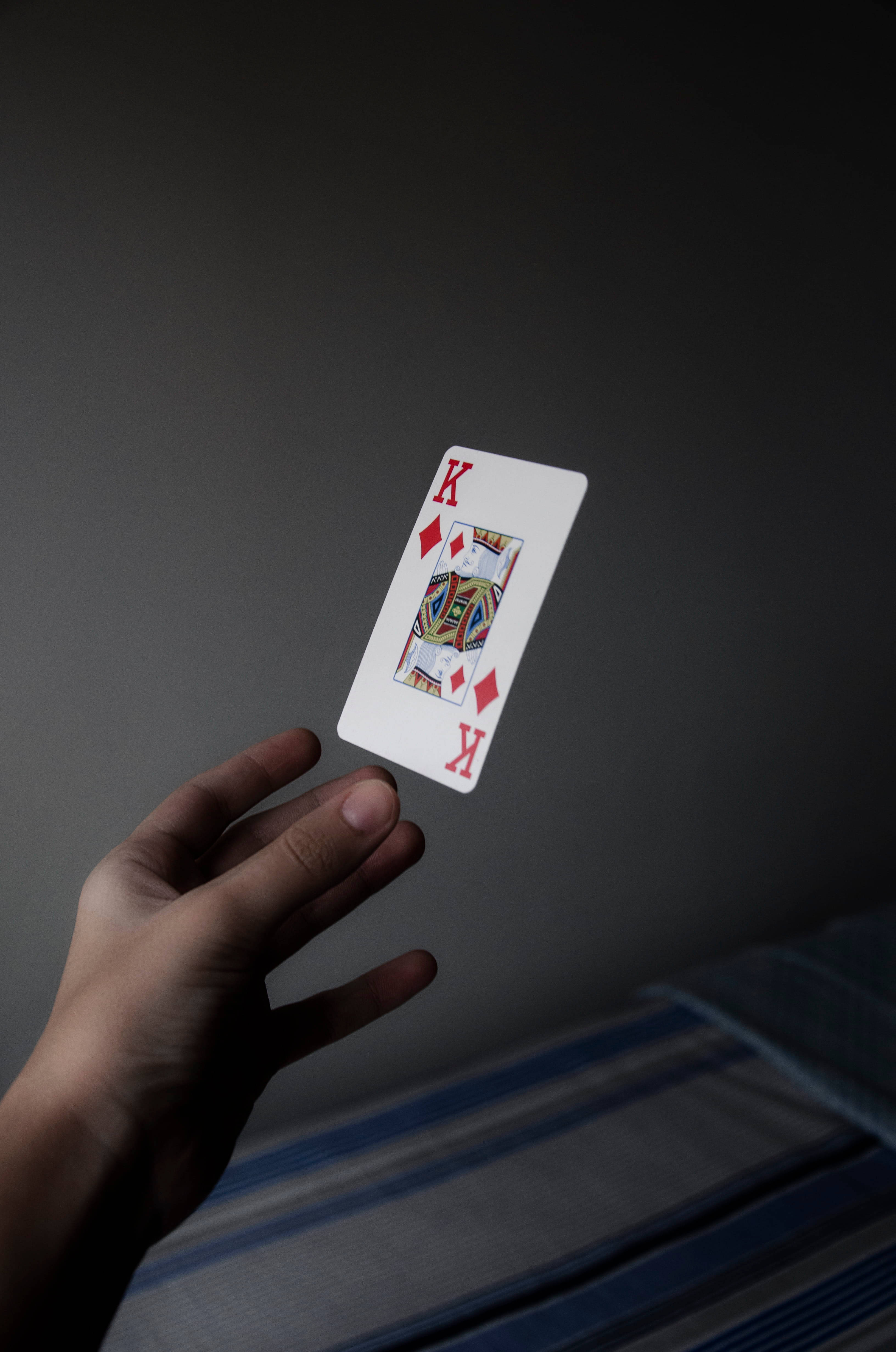 Playing Cards 桌布 壁紙 — 一隻手輕輕地拿著一張方塊K撲克牌，背景是深灰色，光線柔和。