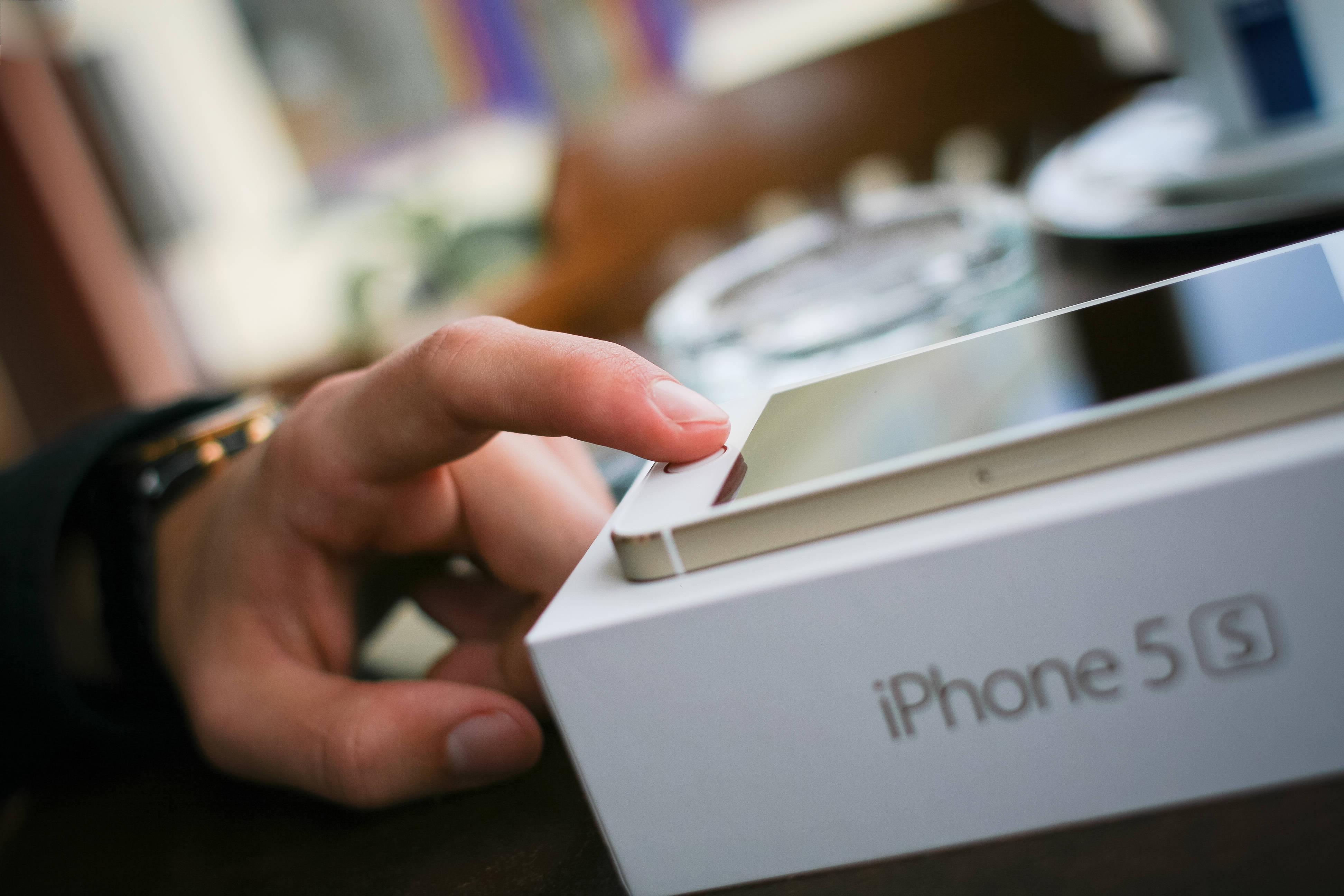 original iPhone 5 桌布 壁紙 — 一隻手輕輕揭開白色 iPhone 5s 盒子的蓋子，露出裡面時尚的銀色手機。
