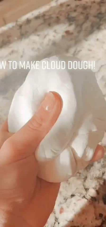 slime 桌布 壁紙 — 一隻手輕輕擠壓柔軟的白色雲朵麵團，放在有斑點的檯面上。