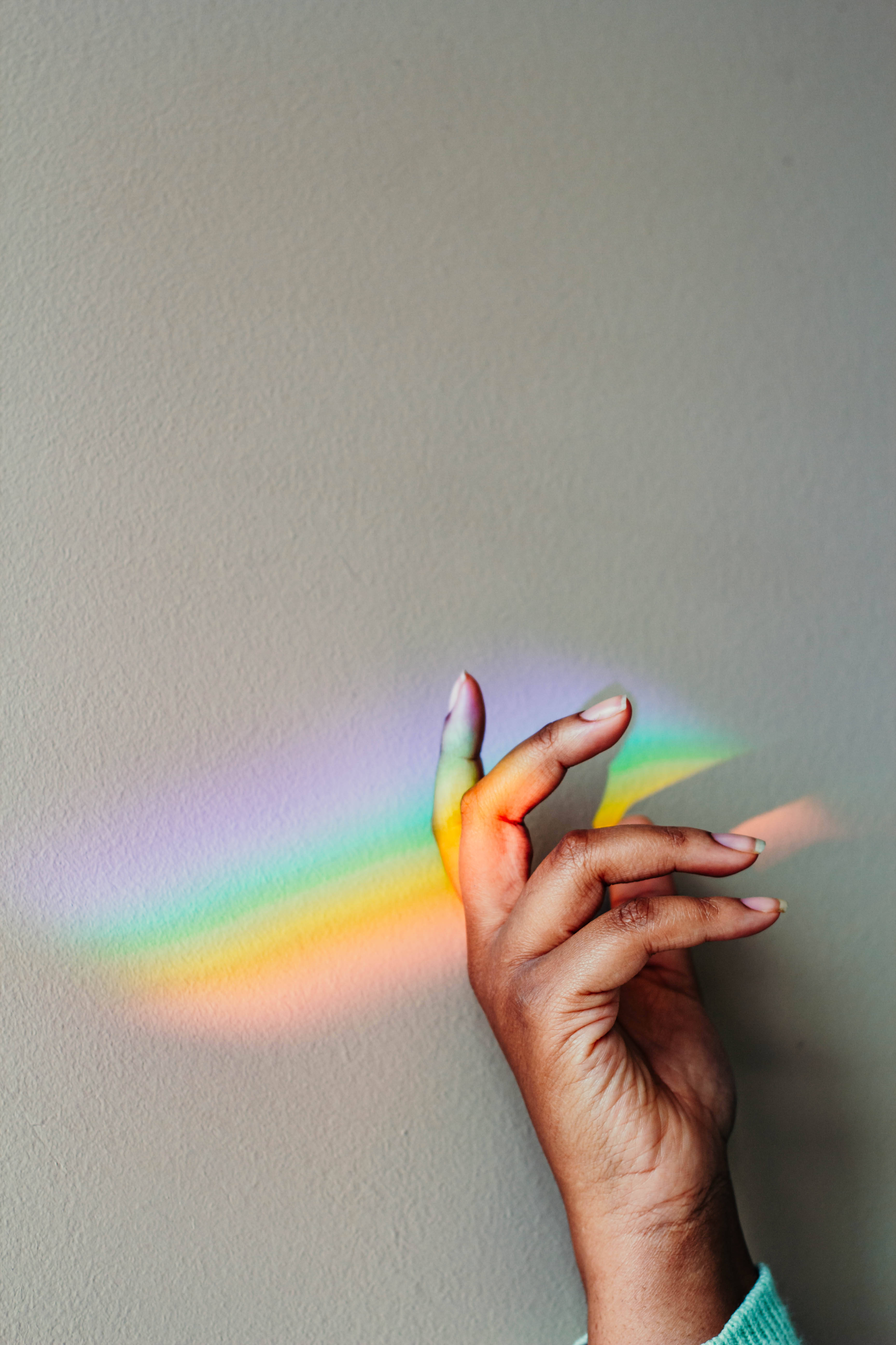 Prism 桌布 壁紙 — 一隻手輕輕觸摸投射在素牆上的鮮豔彩虹光投影，創造出色彩繽紛的驚奇時刻。