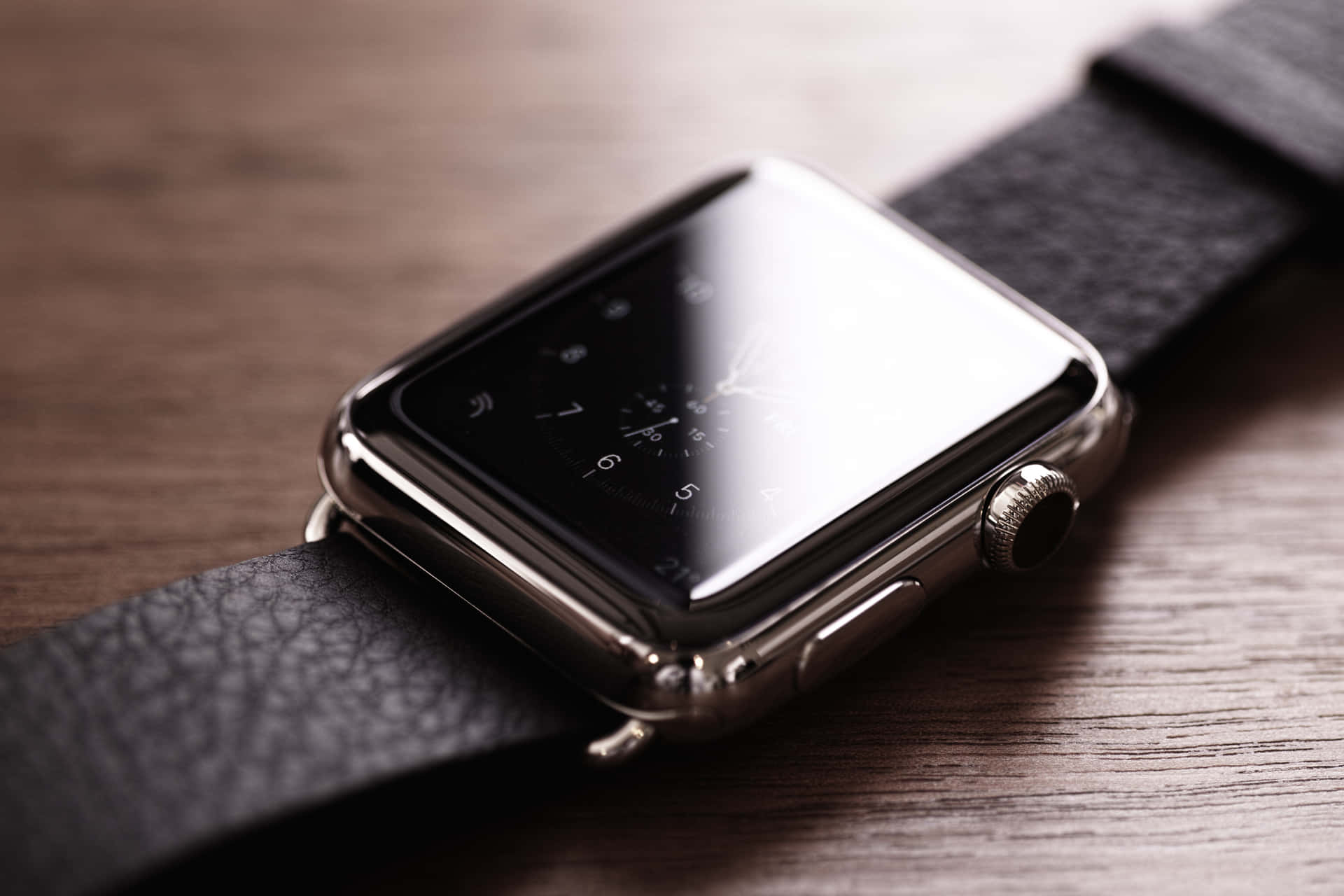 Apple Watch 動態 桌布 壁紙 — 一隻時尚的銀色智慧手錶搭配黑色皮帶，放置在溫暖的木質表面上，其反光螢幕顯示經典的類比時鐘面。