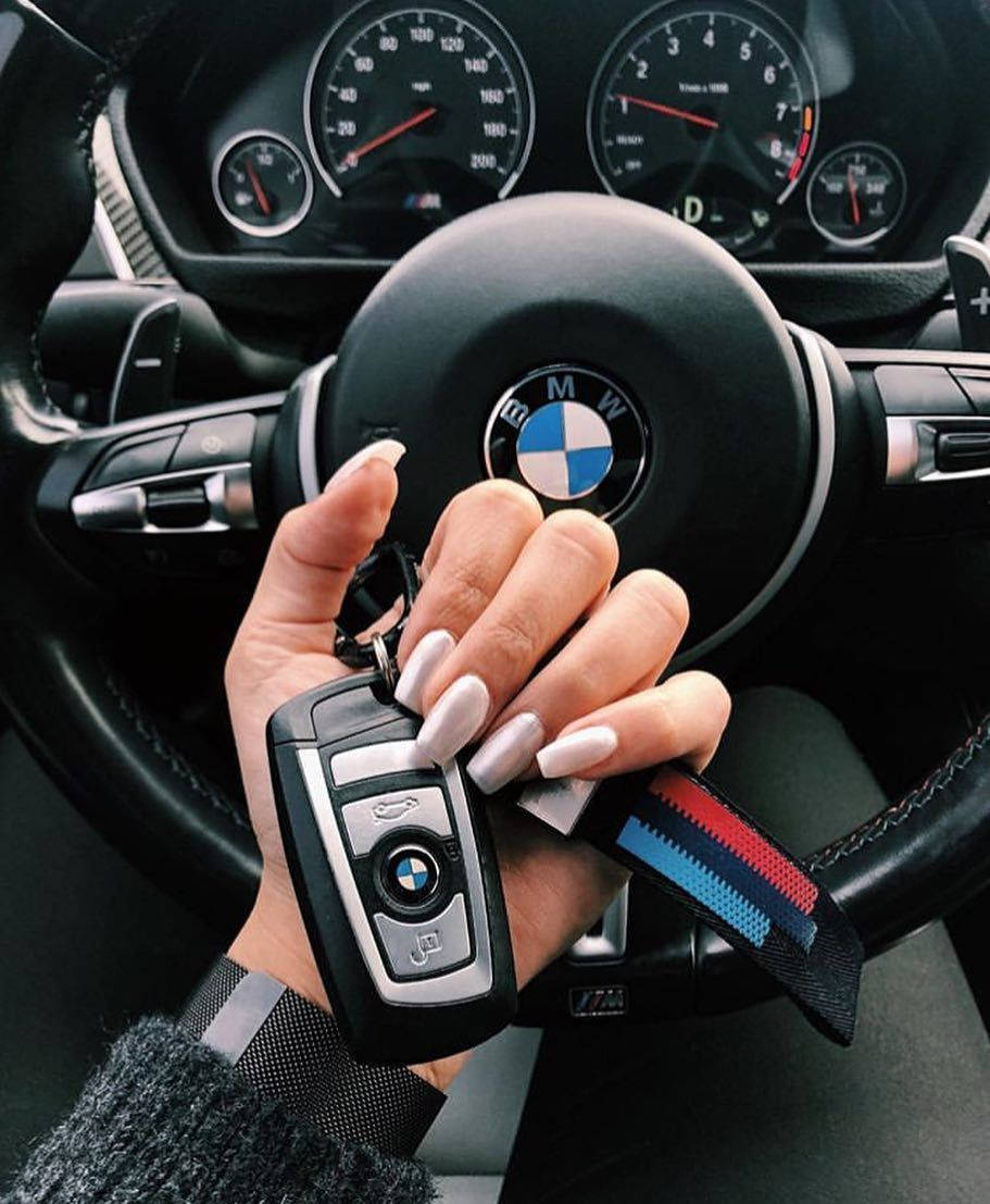 Woman 桌布 壁紙 — 一隻有修甲的手在汽車方向盤和儀表板前拿著BMW車鑰匙。