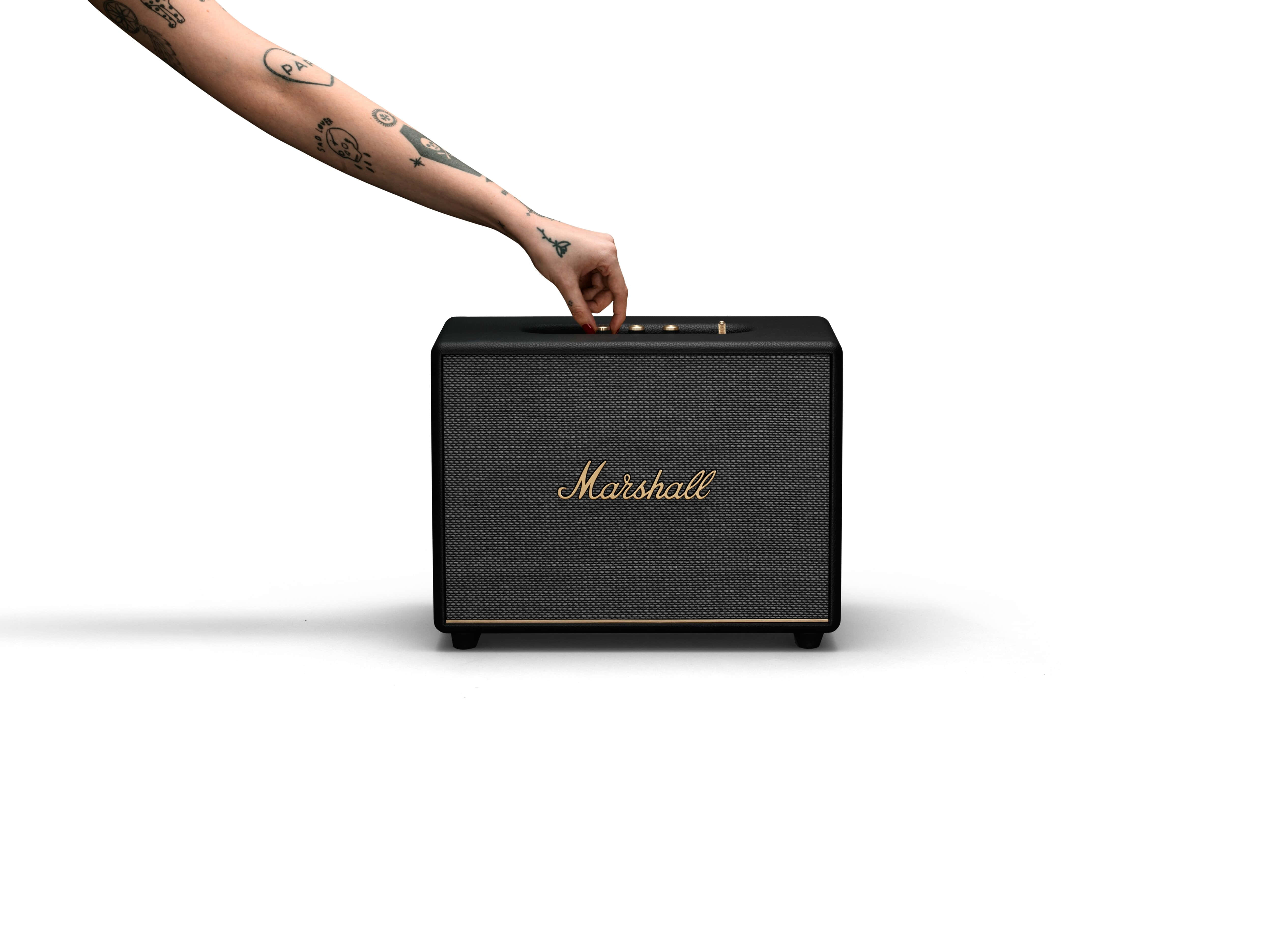Marshall 桌布 壁紙 — 一隻有刺青的手臂伸下來調整黑色Marshall喇叭上的旋鈕，背景是純白色。