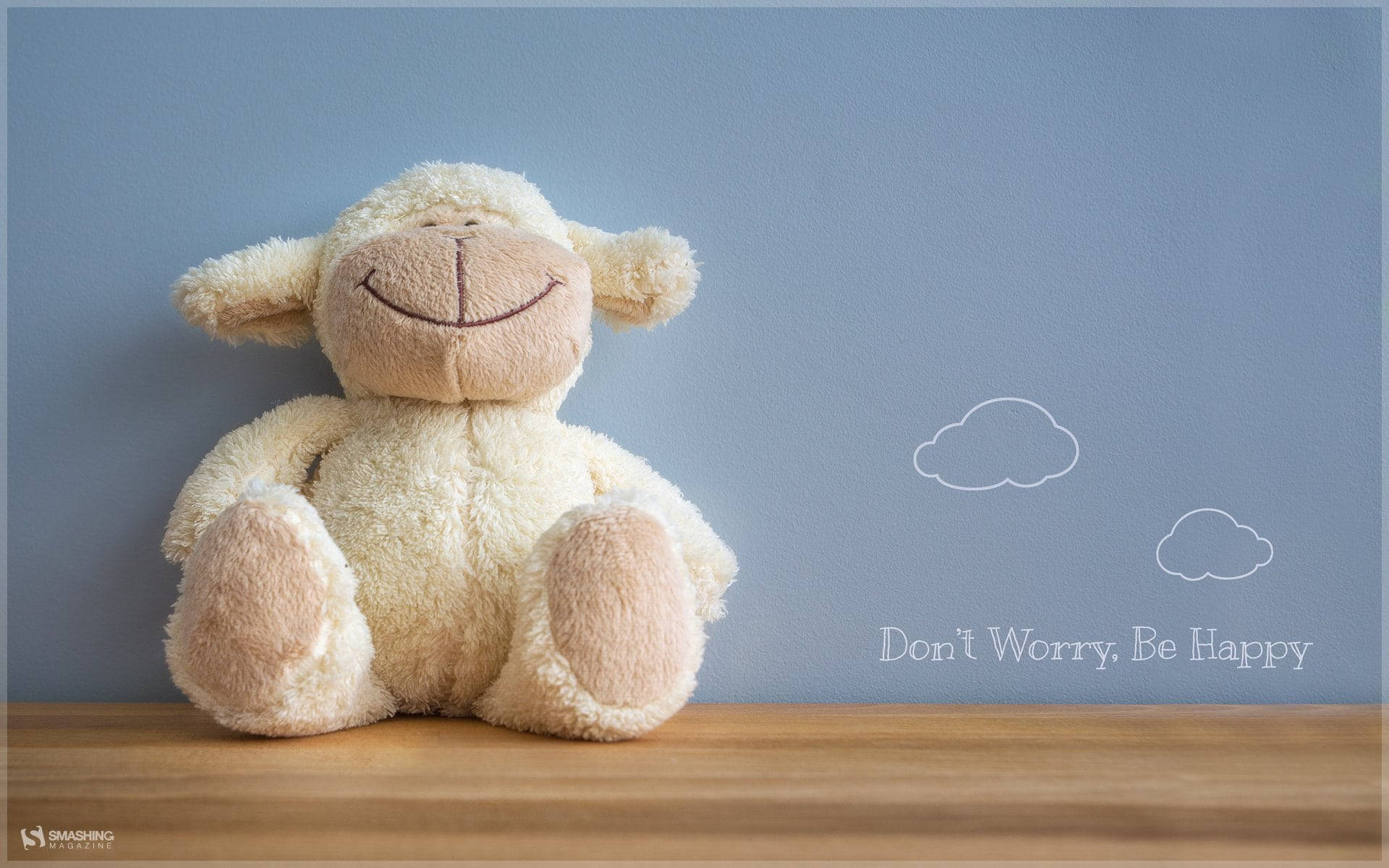 木架上微笑的毛絨羊，帶有「Don't Worry Be Happy」文字和雲朵圖案。