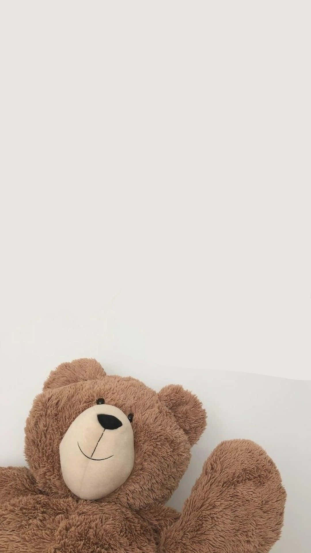 Teddy Bear 桌布 壁紙 — 一隻柔軟的棕色泰迪熊，帶著簡單的縫線微笑，靠在純白色的背景上。
