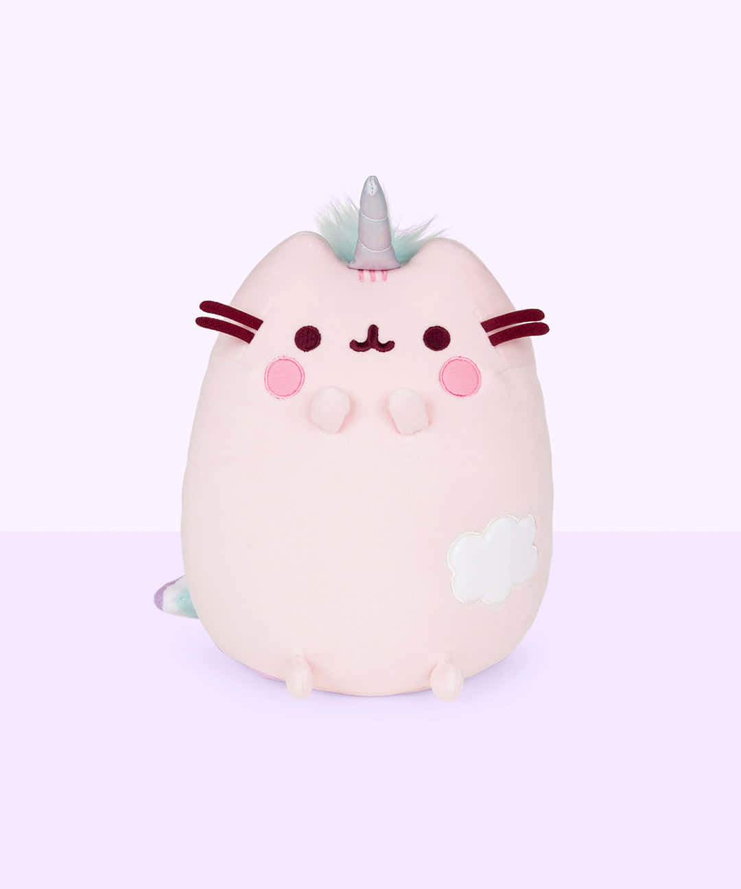pusheen 動圖 桌布 壁紙 — 一隻柔軟粉紅色毛絨獨角貓，帶有銀色角和雲朵補丁，坐在淡紫色背景前。