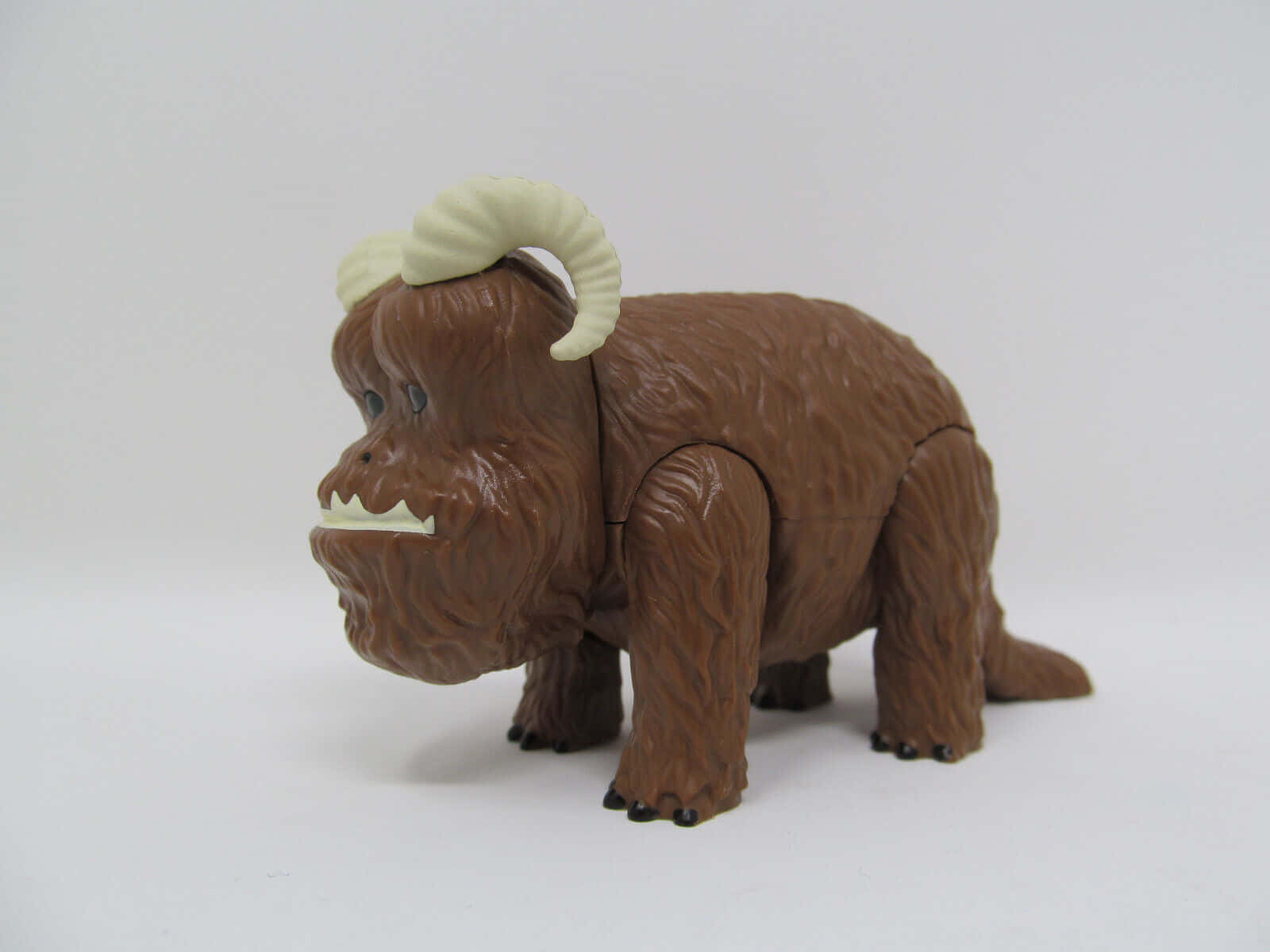 Bantha 桌布 壁紙 — 一隻棕色塑膠玩具野獸，帶有奶油色彎曲的角，站在純白色背景前。