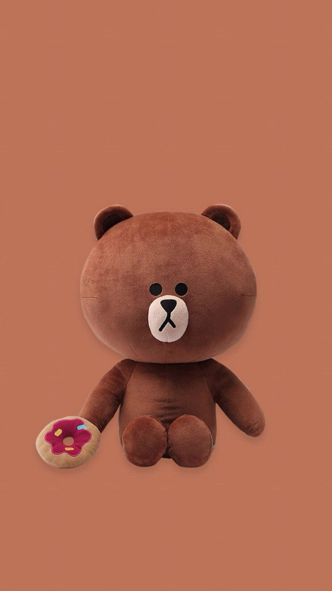 Line 桌布 壁紙 — 一隻棕色絨毛熊，臉部簡單，坐在純色陶土背景前，拿著一個粉色糖霜甜甜圈。