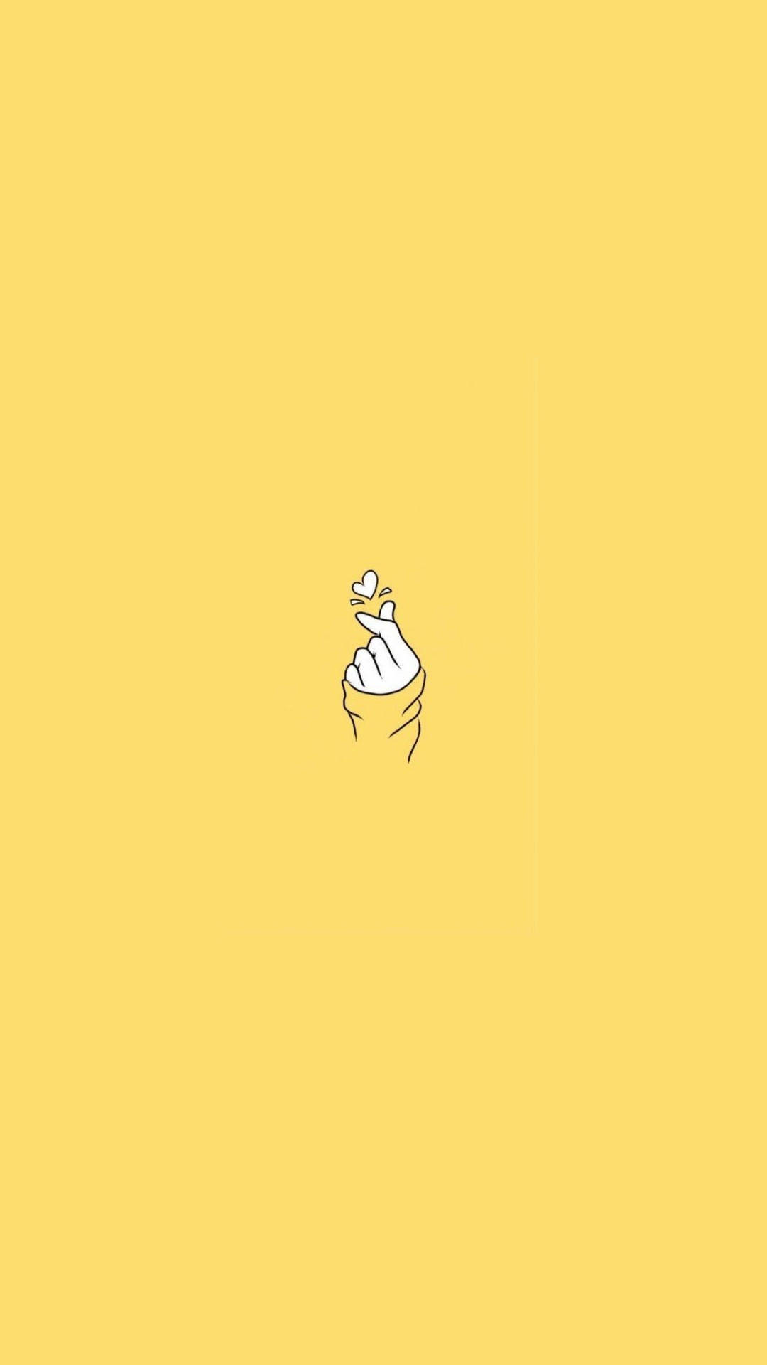 Pastel Yellow Aesthetic 桌布 壁紙 — 一隻極簡線條藝術的手在純黃色背景上做出心形手勢。