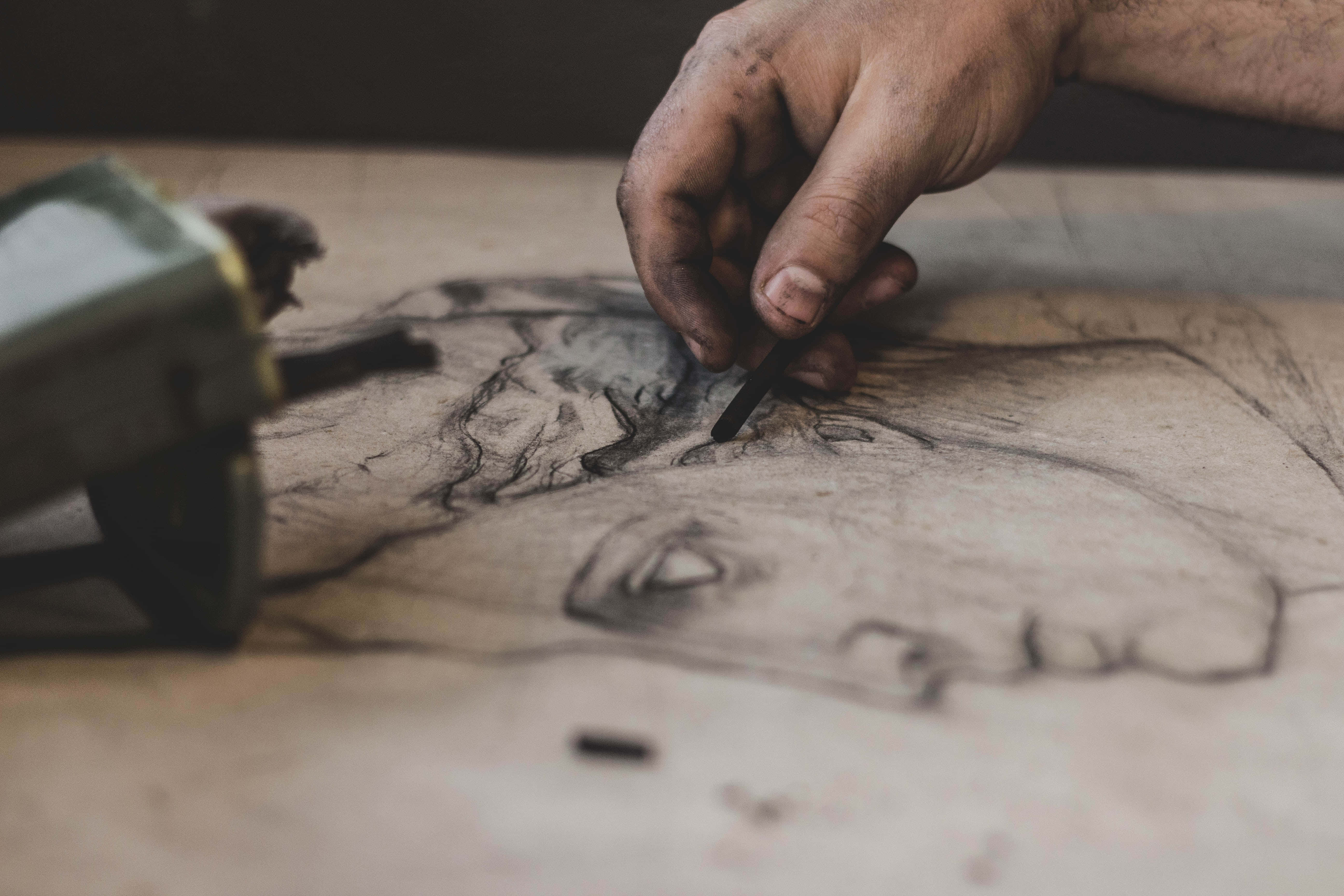 Drawing 桌布 壁紙 — 一隻歷經風霜的手正在紋理紙上用木炭勾勒細緻肖像的特寫。
