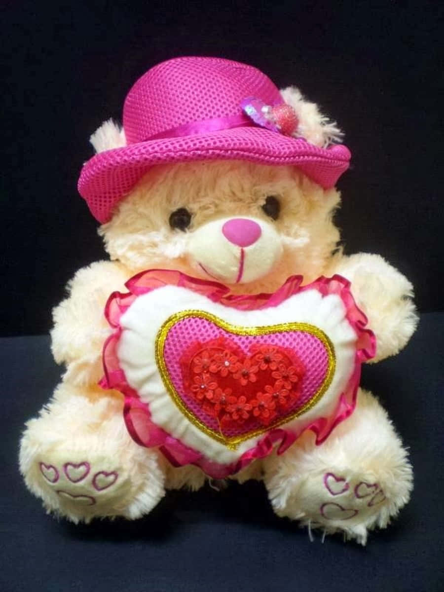 Cute Teddy 桌布 壁紙 — 一隻毛茸茸的奶油色泰迪熊，戴著粉紅色網帽，在深色背景前抱著一個裝飾心形枕頭。