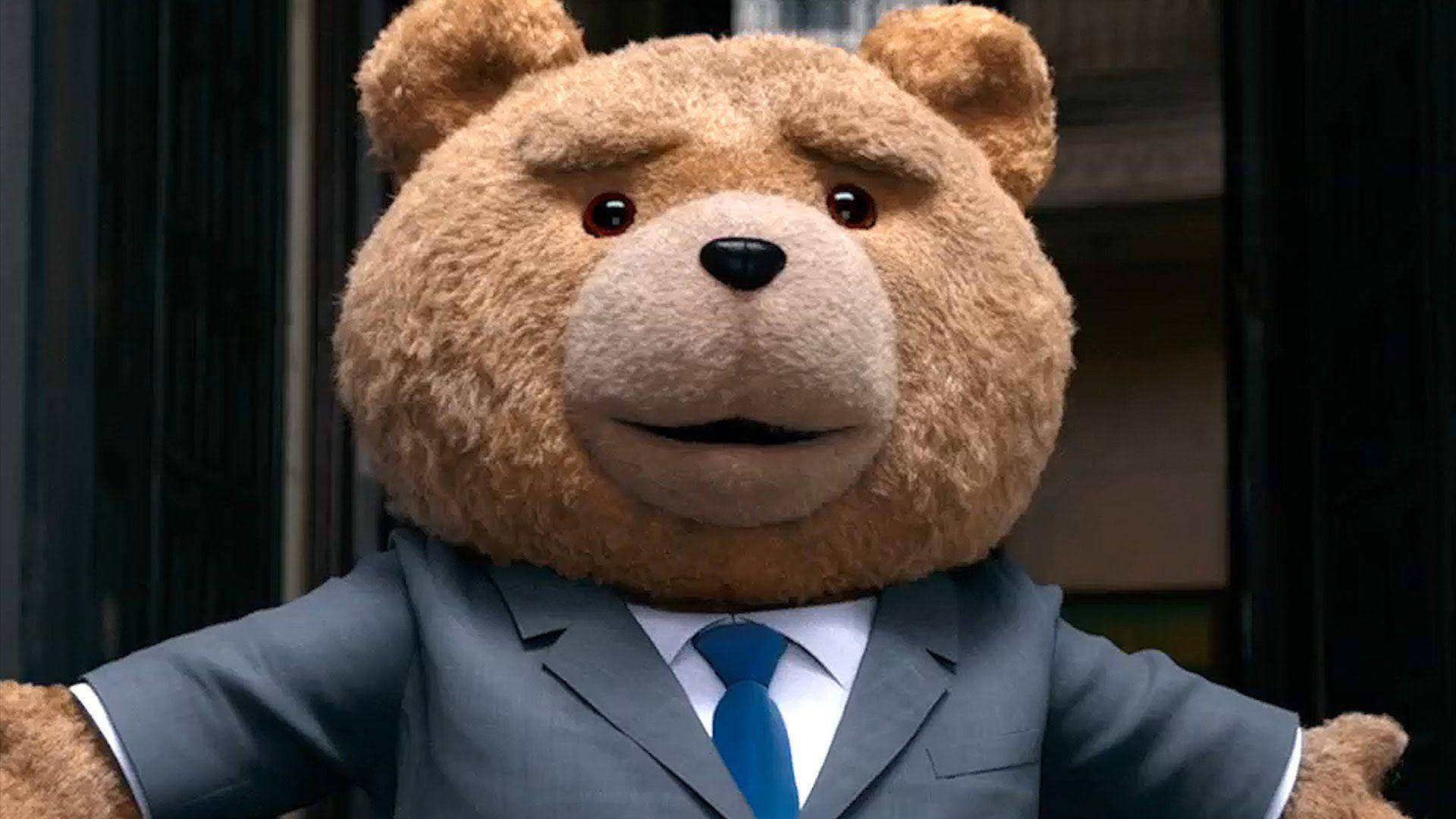 Ted 桌布 壁紙 — 一隻毛茸茸的棕色泰迪熊穿著灰色西裝和藍色領帶，表情驚訝的特寫。
