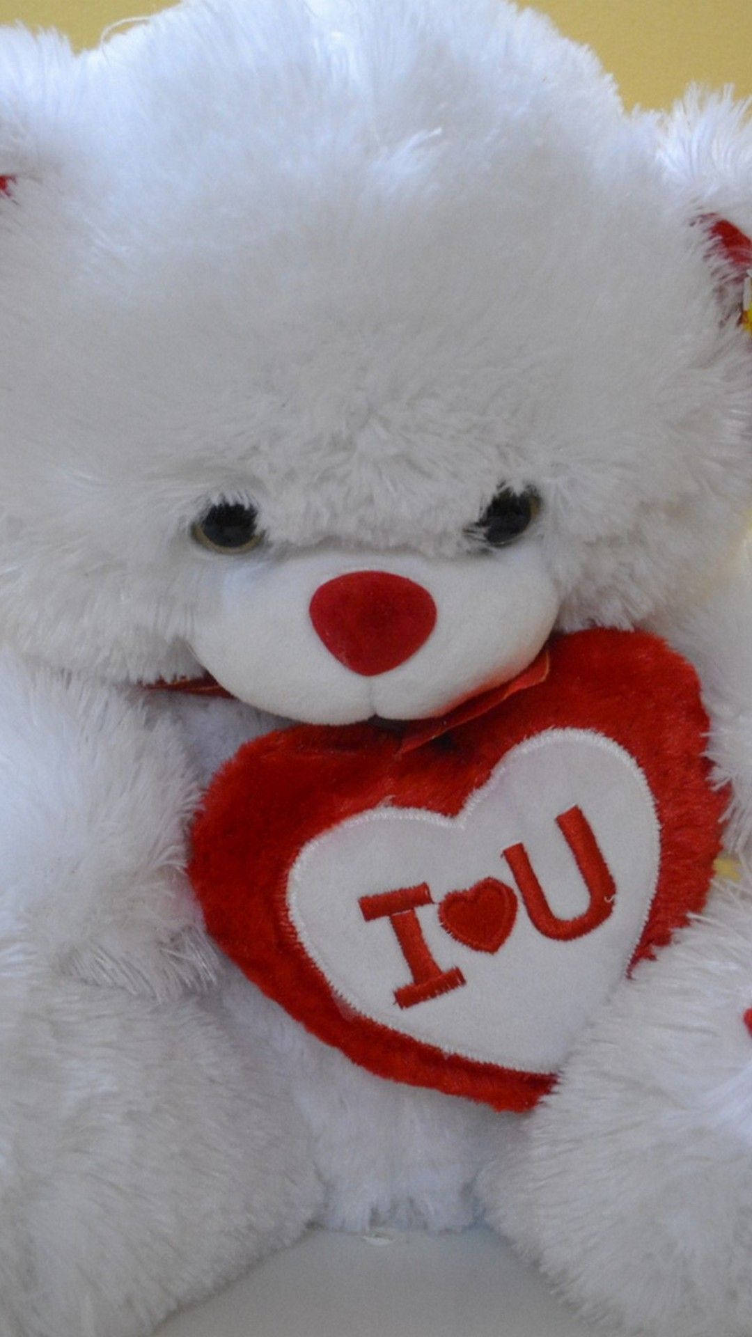 Teddy Bear 桌布 壁紙 — 一隻毛茸茸的白色泰迪熊抱著一個紅色心形枕頭，上面繡有 I heart U 字樣。