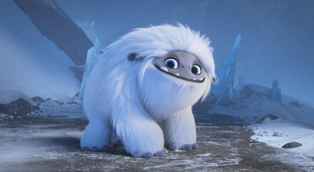 電影動圖 桌布 壁紙 — 一隻毛茸茸的白色雪人，有大大的藍眼睛，坐在有冰晶和岩石地形的雪山景觀中。