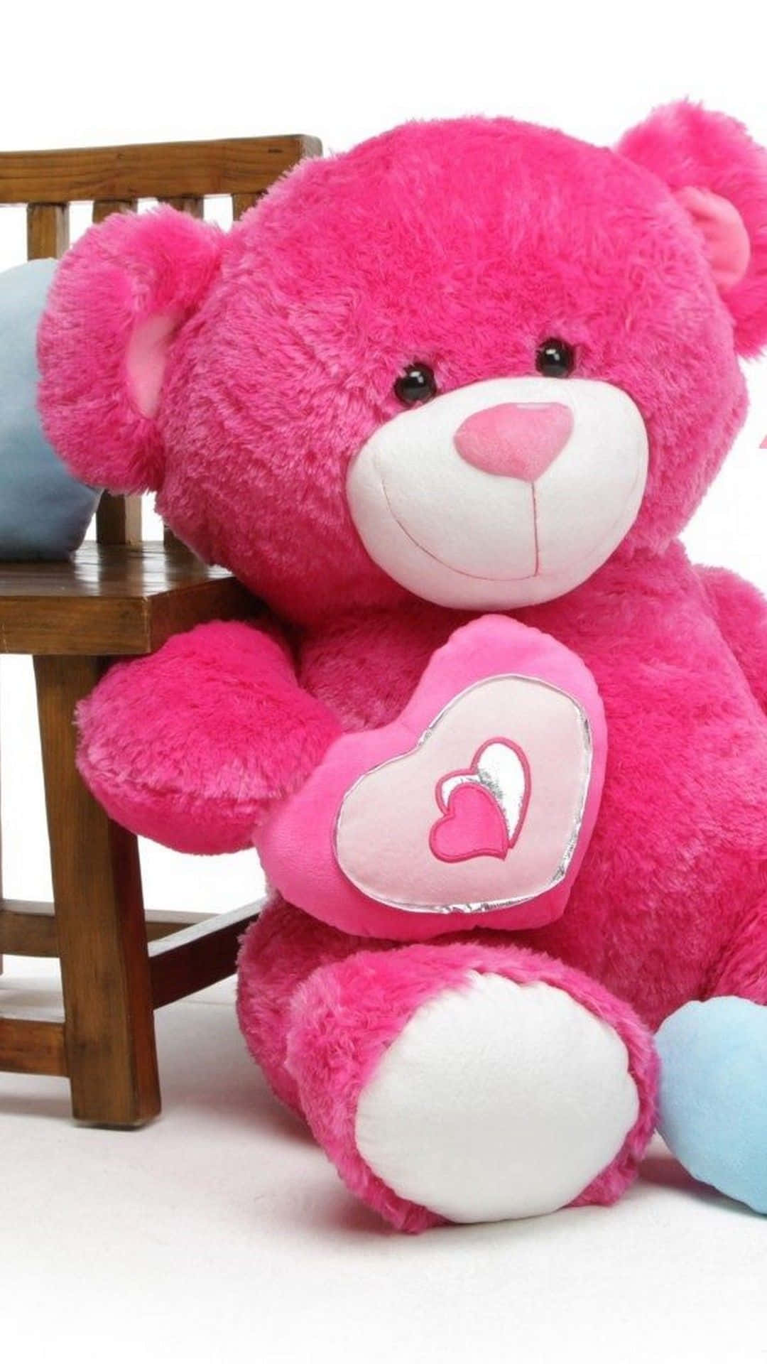 bear love 桌布 壁紙 — 一隻毛茸茸的粉紅色泰迪熊，帶有心形補丁，坐在白色背景的木椅上。
