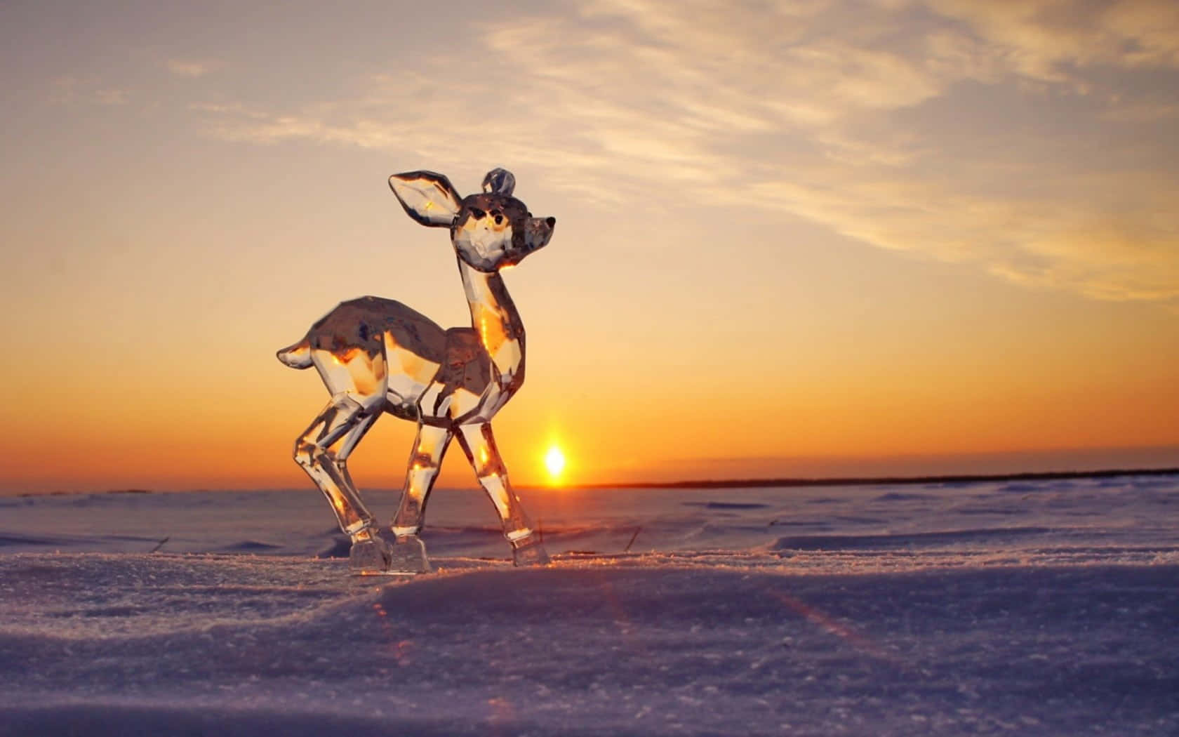 Ice Sculpture 桌布 壁紙 — 一隻水晶鹿雕像優雅地立在雪地上，夕陽散發著溫暖的橙色光芒。