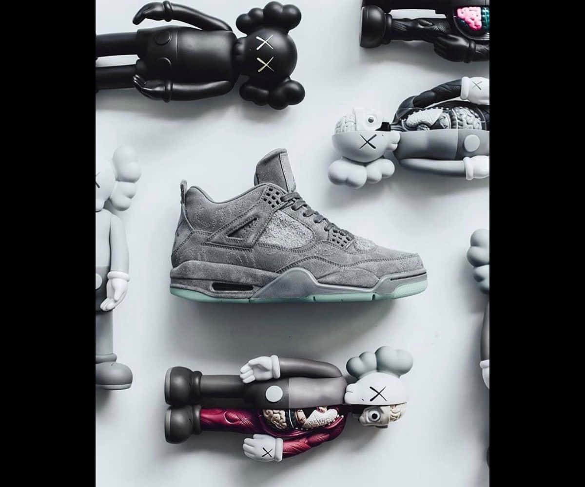 Kaws X Air Jordan 桌布 壁紙 — 一隻灰色麂皮運動鞋置於黑色和灰色KAWS公仔中央，背景為純白平面。