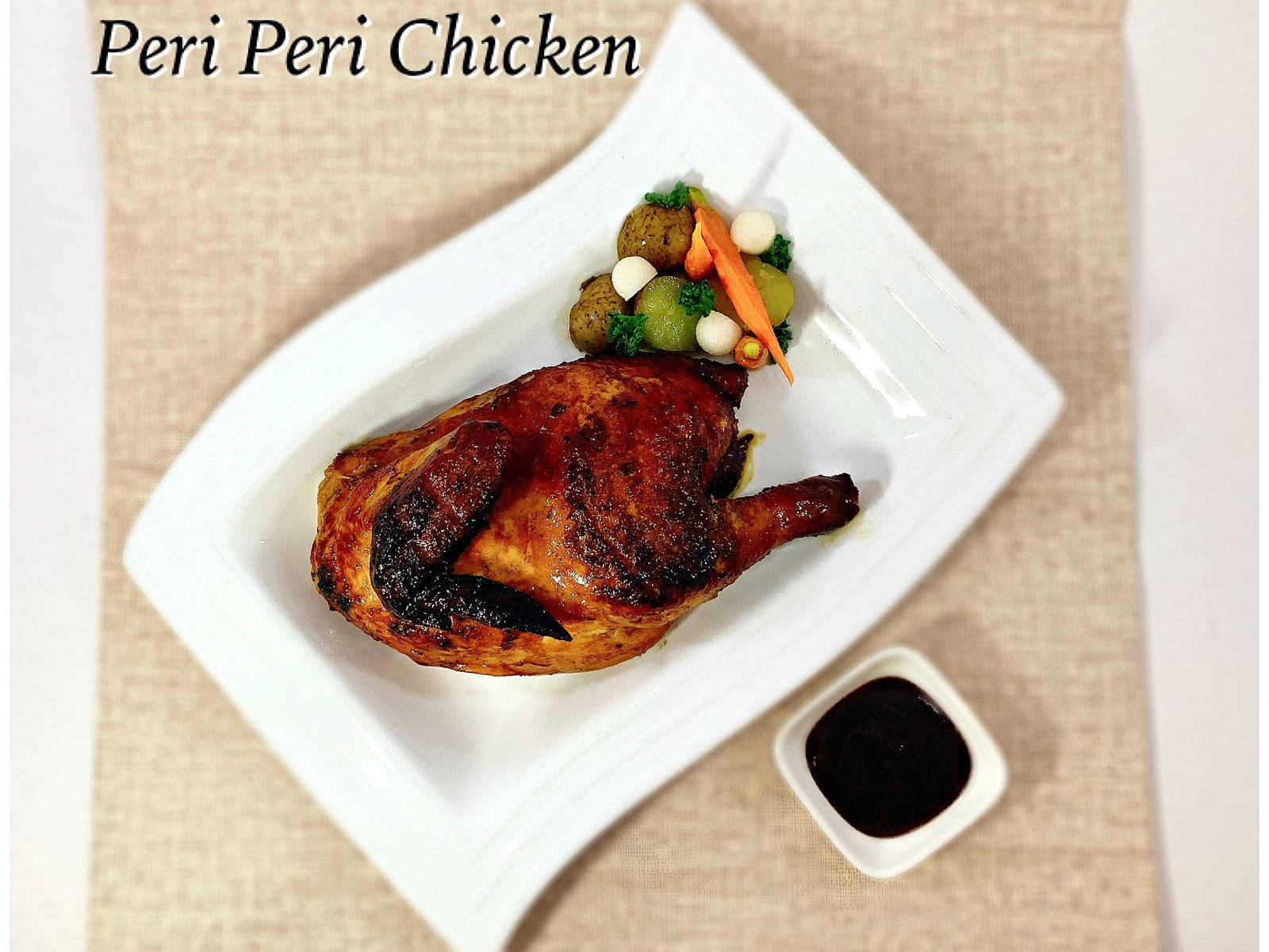 Delicious Food 桌布 壁紙 — 一隻烤 peri peri 雞，皮帶焦黑，放在白色盤子上，旁邊有色彩繽紛的蔬菜和沾醬。