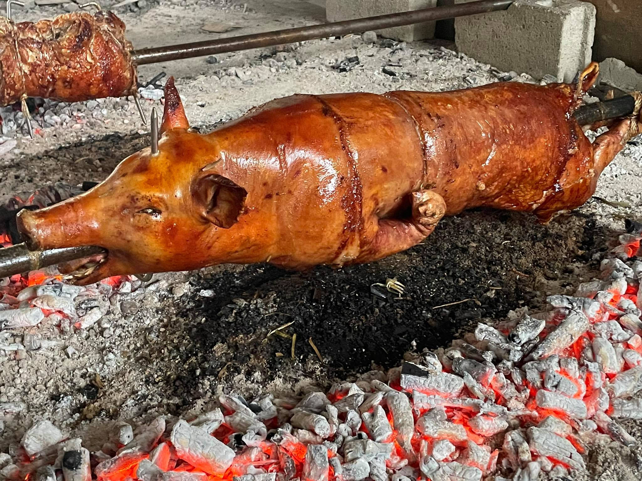 Pig 桌布 壁紙 — 一隻烤全豬在傳統戶外燒烤設置中，在發光的餘燼上旋轉。