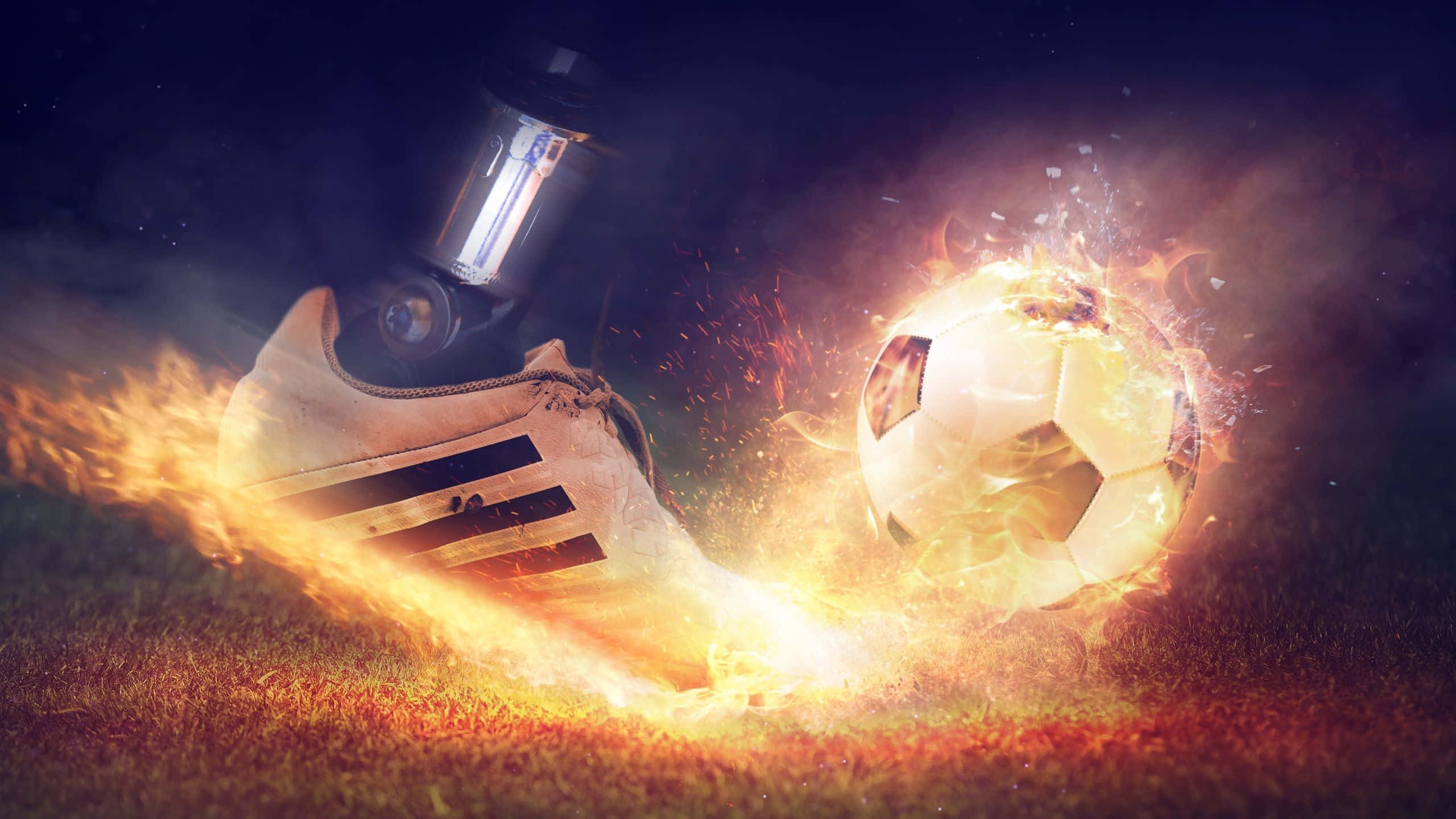 Football On Fire 桌布 壁紙 — 一隻燃燒的足球靴在黑暗天空下的草地上踢出一個火球足球。
