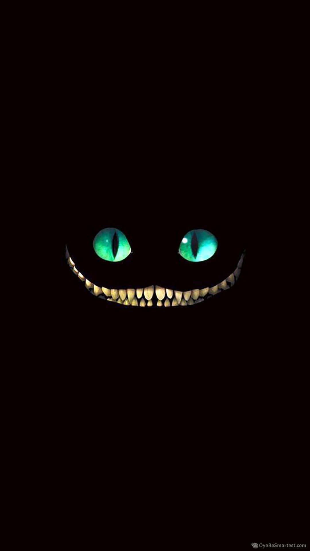 Cartoon Cat Scary 桌布 壁紙 — 一隻發光綠眼的柴郡貓在漆黑背景中咧嘴露出尖牙。