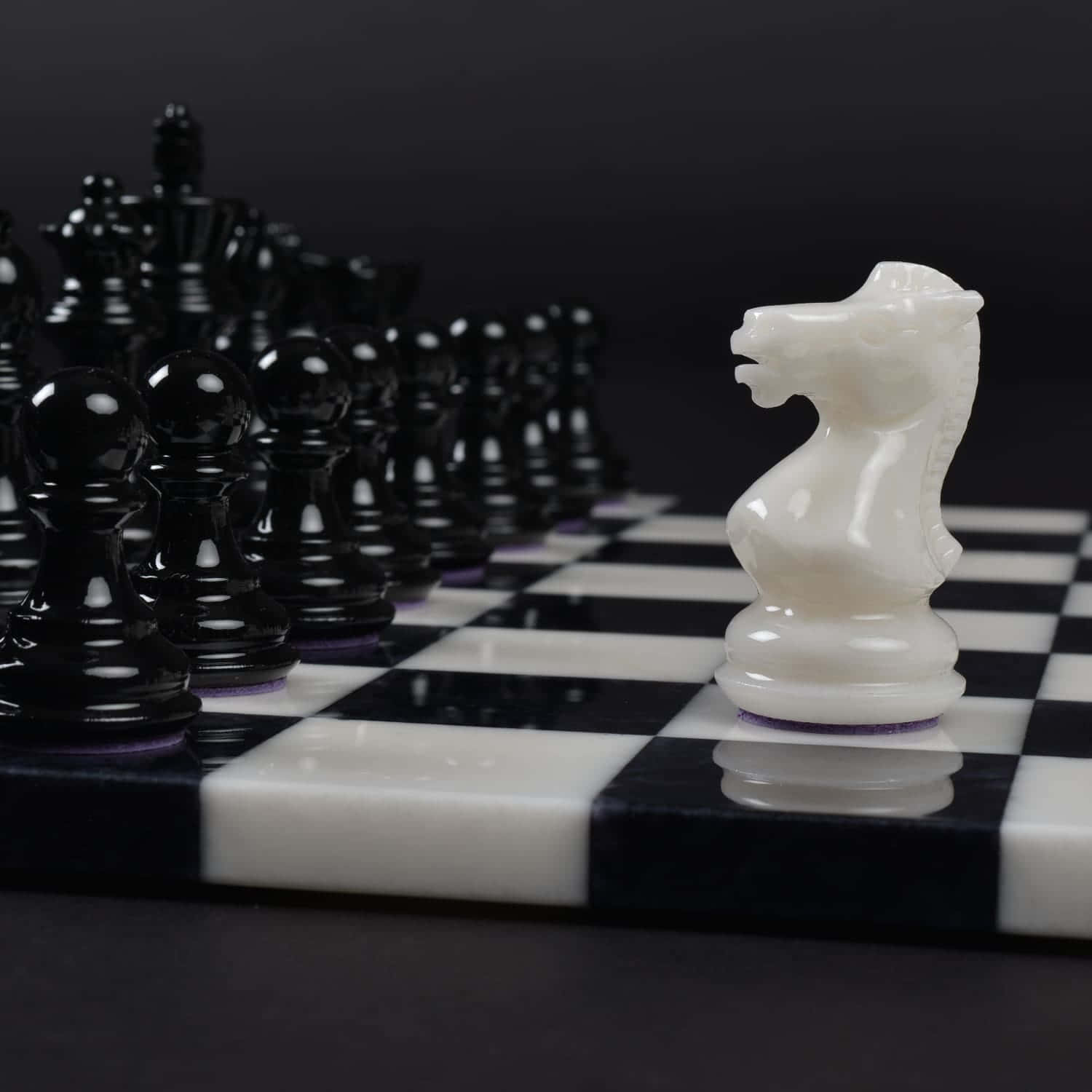 Black And White Chess 桌布 壁紙 — 一隻白色西洋棋騎士站在棋盤上，面對著一群黑色棋子，形成戲劇性的對峙。