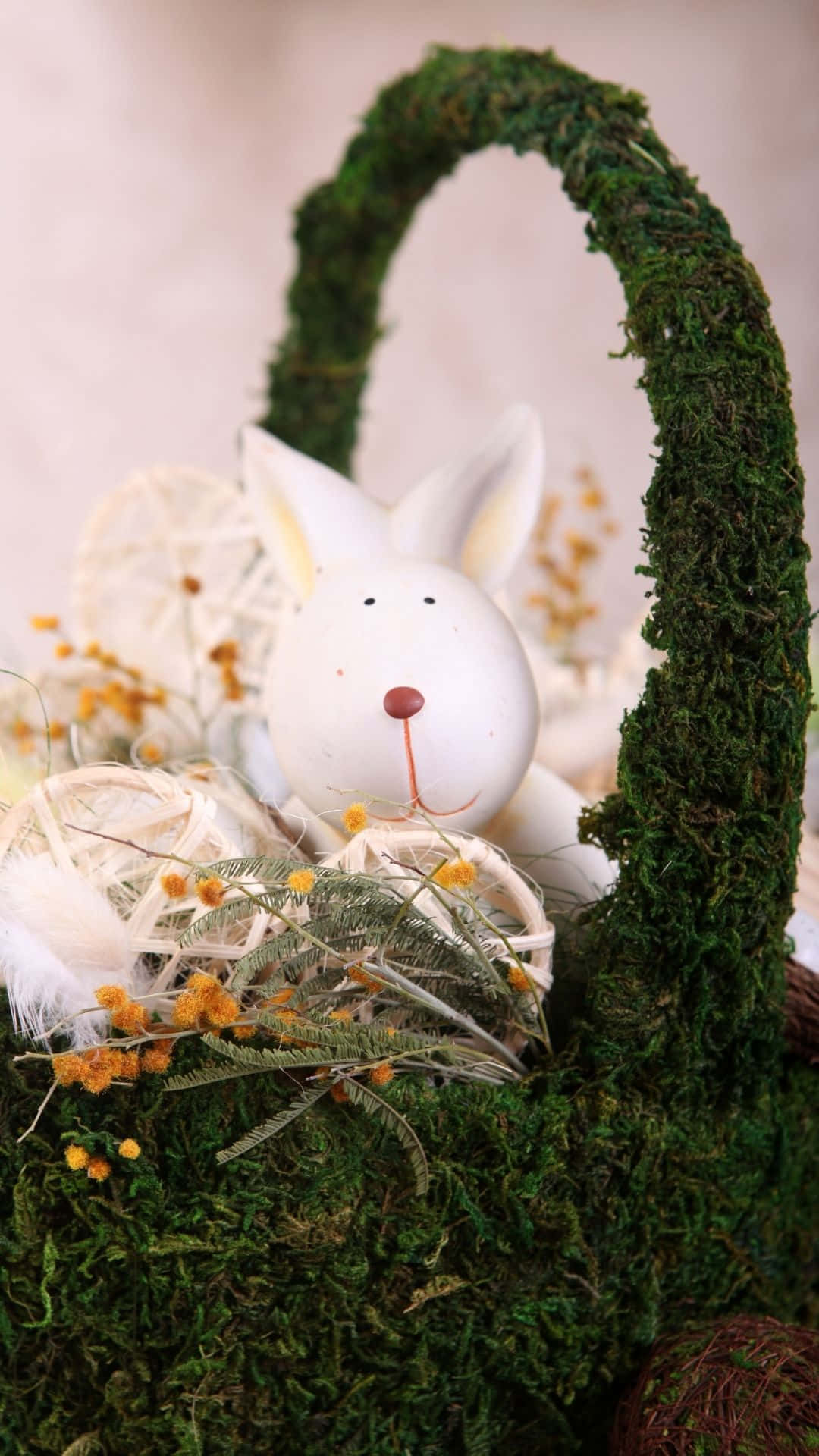 Easter Basket 桌布 壁紙 — 一隻白色陶瓷兔坐在一個佈滿苔蘚的籃子裡，籃子裡裝滿了乾草和小黃花。