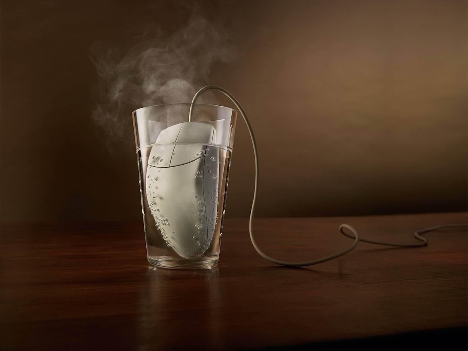 Mouse 桌布 壁紙 — 一隻白色電腦滑鼠浸在一杯水中，散發出蒸氣，背景是溫暖的棕色。