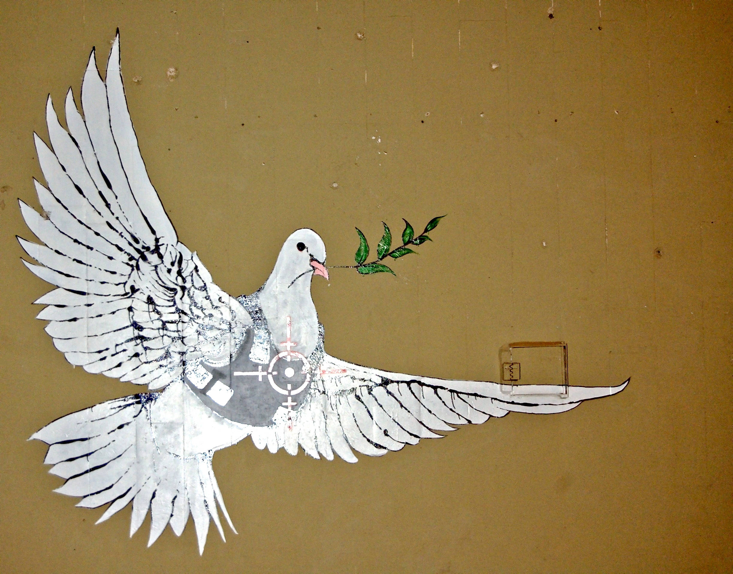 Banksy 桌布 壁紙 — 一隻白鴿展開翅膀，叼著橄欖枝，胸前畫有一個靶心，背景是米色牆壁。