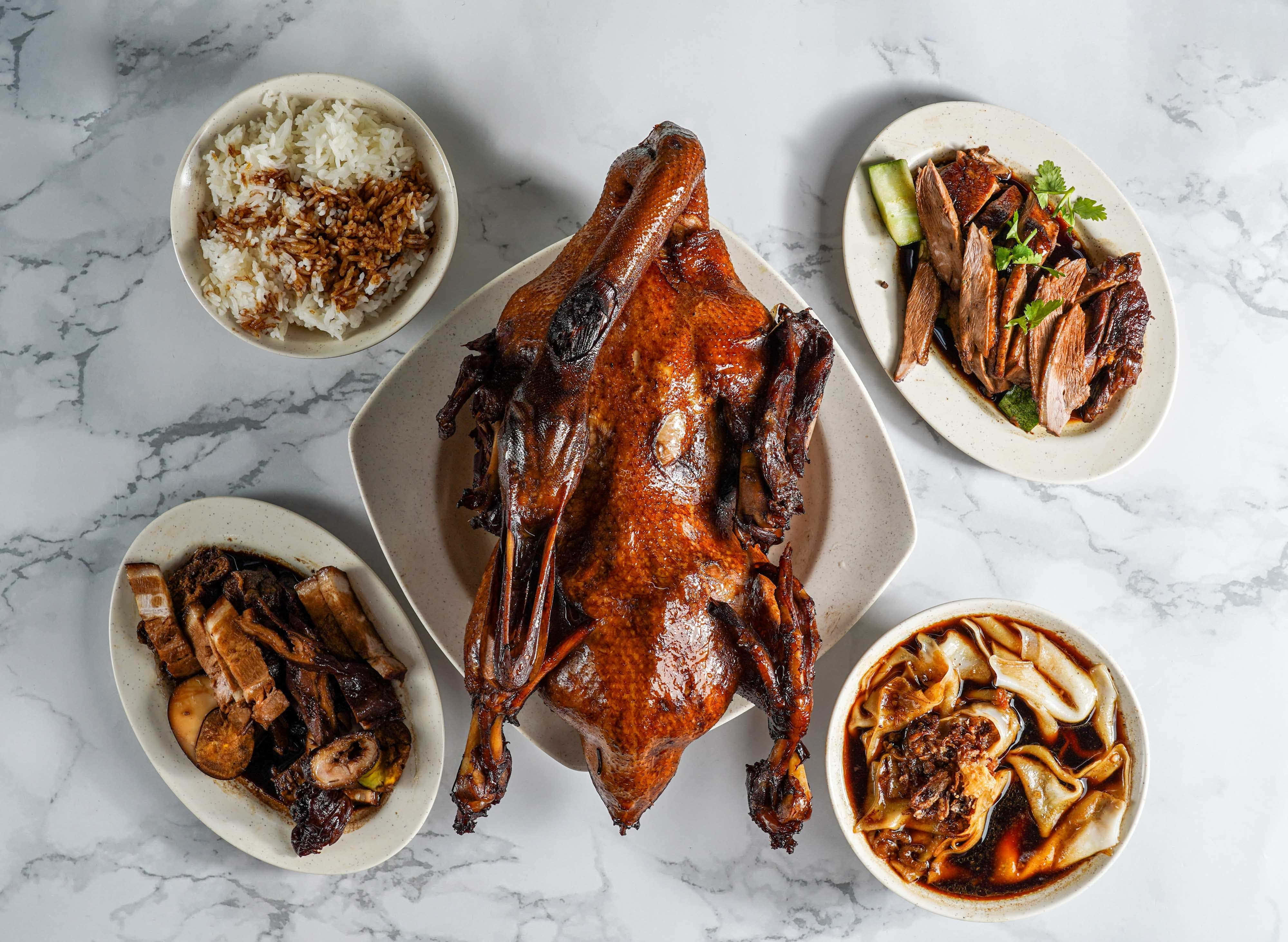 Food Photography 桌布 壁紙 — 一隻皮光肉滑的整隻烤鴨坐在正中央，被四道配菜圍繞，放在白色大理石桌面上。
