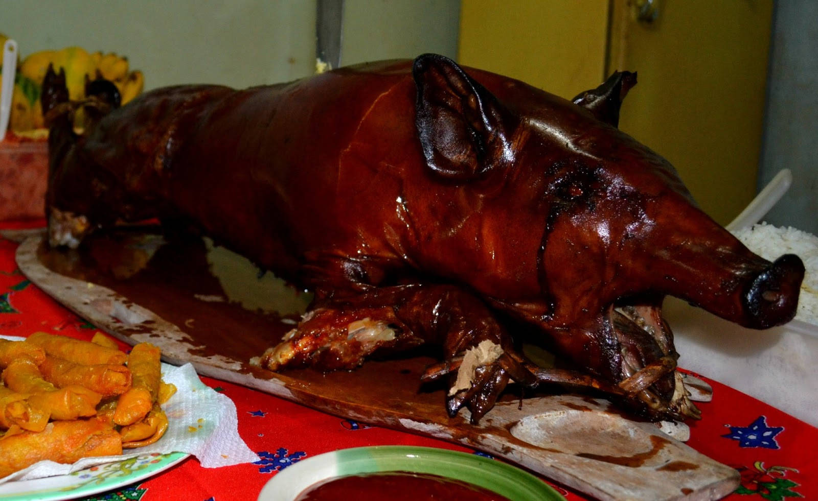 Pig 桌布 壁紙 — 一隻皮脆焦糖化的整隻烤豬放在木盤上，旁邊有春捲和米飯，置於節日桌布上。