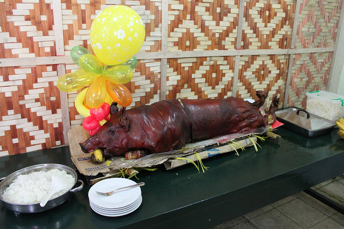 Pig 桌布 壁紙 — 一隻皮脆肉嫩的原隻烤豬放在紙托盤上，旁邊有白飯和色彩繽紛的氣球裝飾。