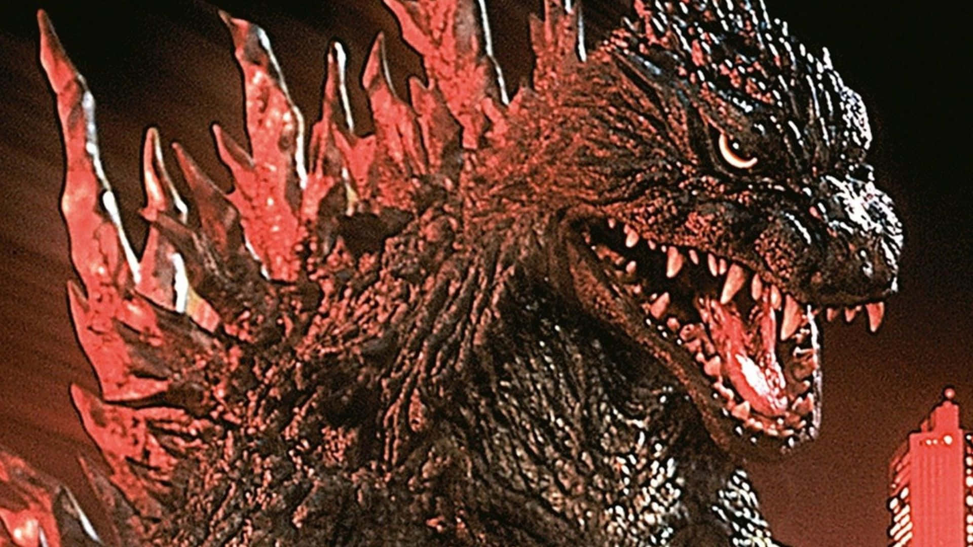 Godzilla 2000 桌布 壁紙 — 一隻眼睛發光、背鰭火紅的怪獸哥吉拉，在黑暗的城市天際線前發出威脅性的咆哮。
