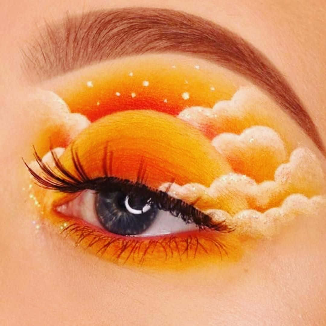Eyes 桌布 壁紙 — 一隻眼睛的特寫，帶有充滿活力的日落妝容，包括橙色漸變雲朵和亮粉。