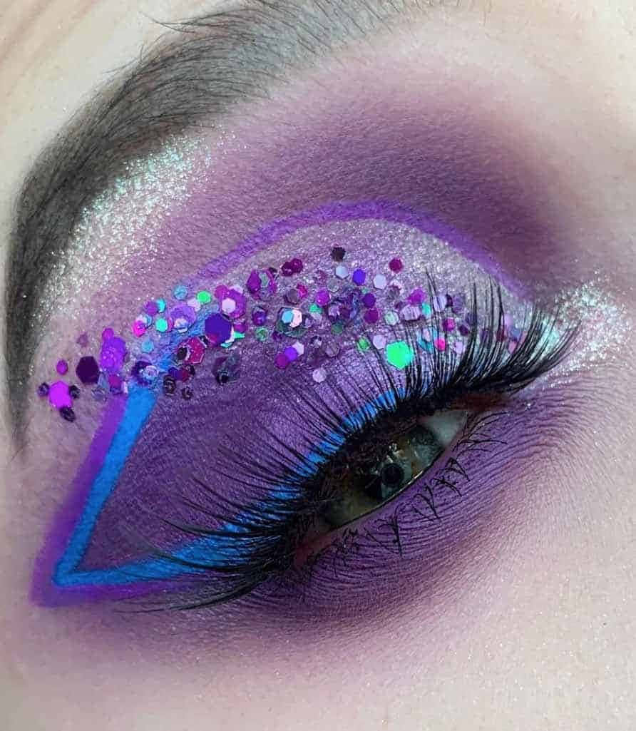 Purple Eye Shadow 桌布 壁紙 — 一隻眼睛的特寫，飾有閃亮的紫色和藍色化妝品以及大膽的幾何眼線。