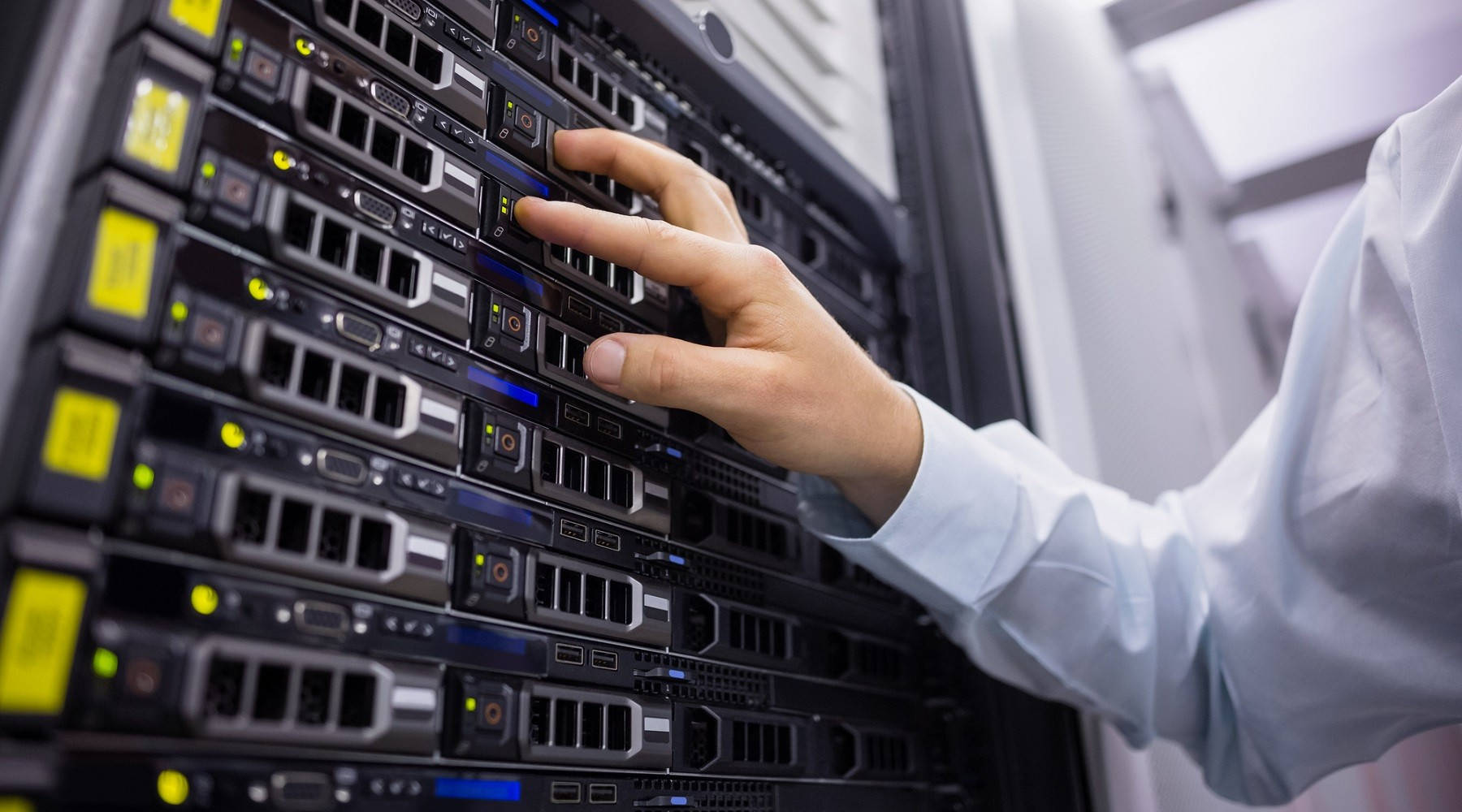 data 桌布 壁紙 — 一隻穿著白襯衫的手正在小心調整一個帶有發光指示燈和閃爍端口的伺服器機架。