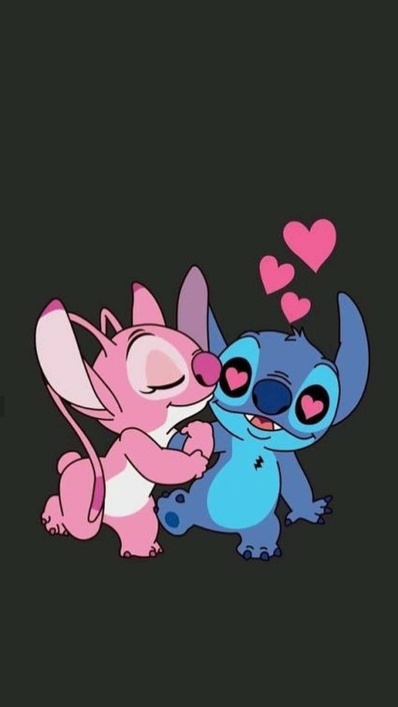 Stitch And Angel 桌布 壁紙 — 一隻粉紅色老鼠和一個藍色外星人在黑暗背景上分享一個甜蜜的吻，周圍有漂浮的心形。